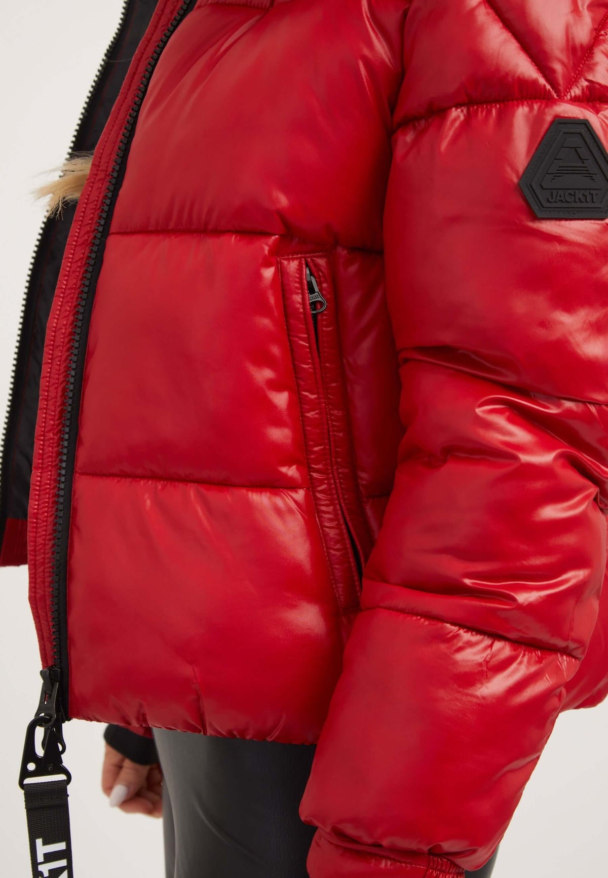 Red puffer jacket showing the side detail and texture with durable fabric and a zip pocket.