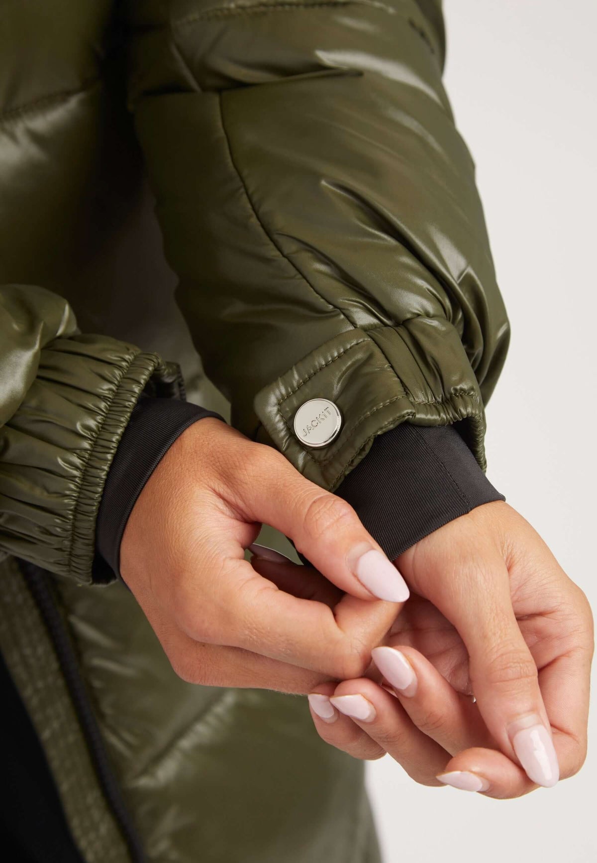 Close-up of hands adjusting the cuff of EZ Slick Ultra Long Coat Olive, showcasing the stylish design of an extra long puffer coat.