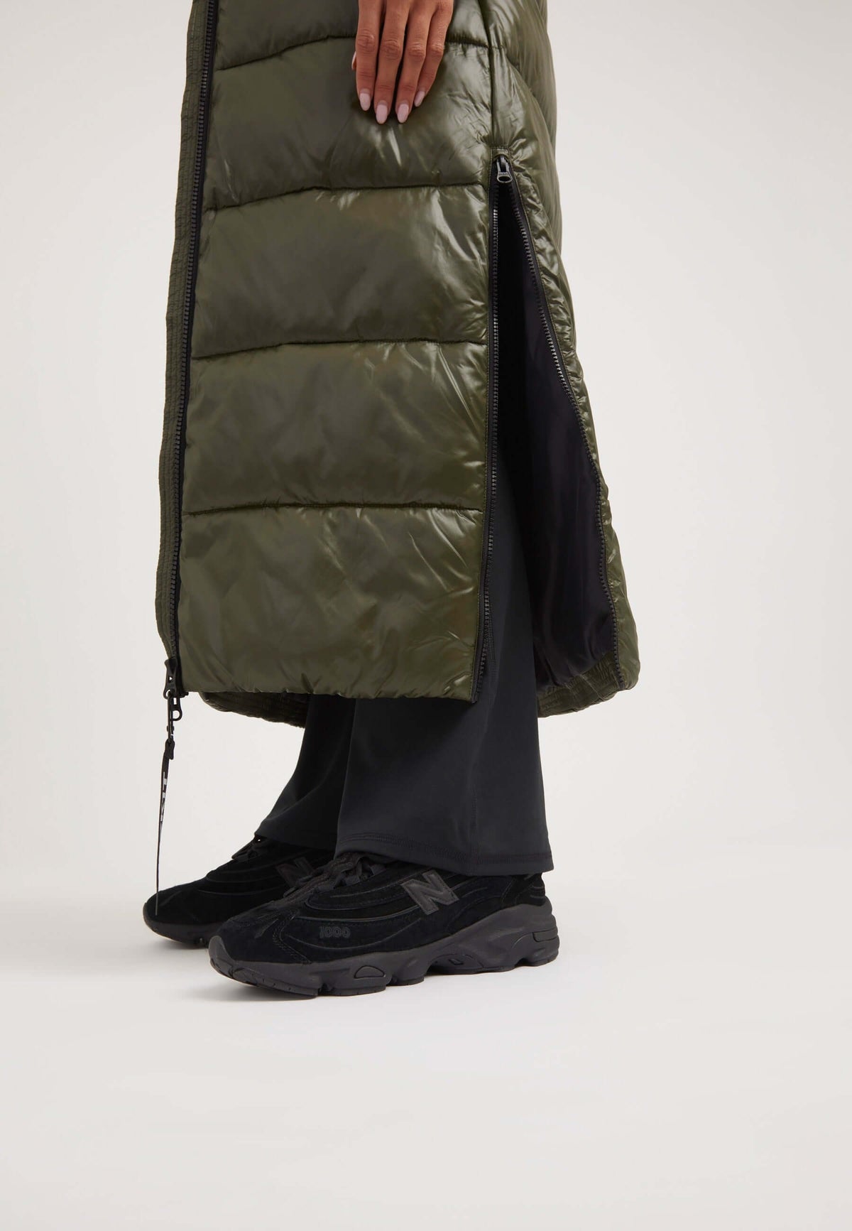 Model wearing EZ Slick Ultra Long Coat Olive with side-opening vent and black sneakers, showcasing the extra long puffer coat.