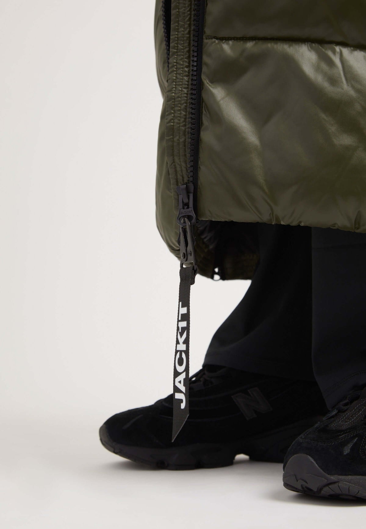 Model showcasing the EZ Slick Ultra Long Coat Olive with a focus on the side zip and JACKIT tag, emphasizing the extra long puffer coat design.