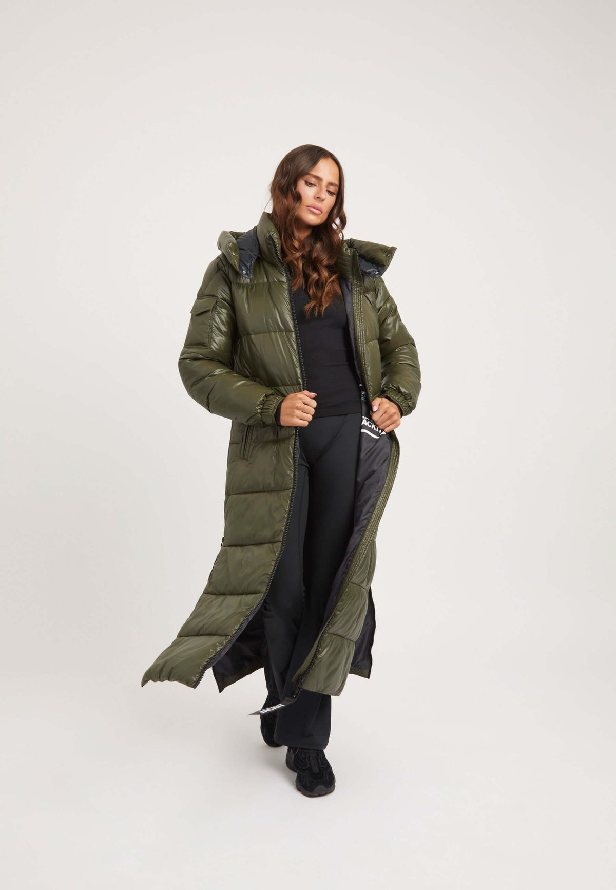 Model wearing EZ Slick Ultra Long Coat in olive, featuring a full length silhouette as an Extra long puffer coat.