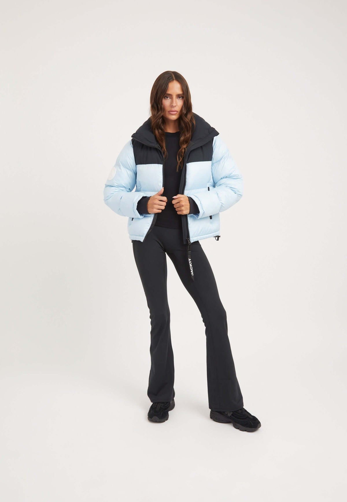Model wearing a Diamond Funnel Jacket in Powder Blue Black, featuring a funnel neck, tapered racer fit, and contrasting color panels.