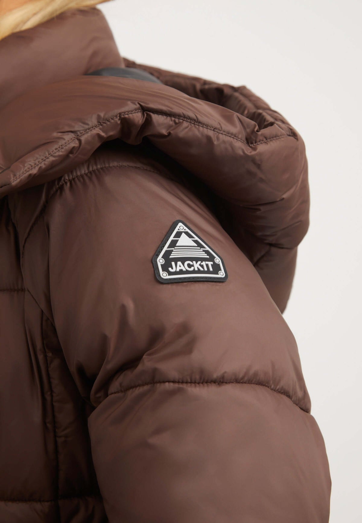 Close-up of the Cloud Boss Coat Mid Brown showing the reflective badge, highlighting the womens long puffer coat style.