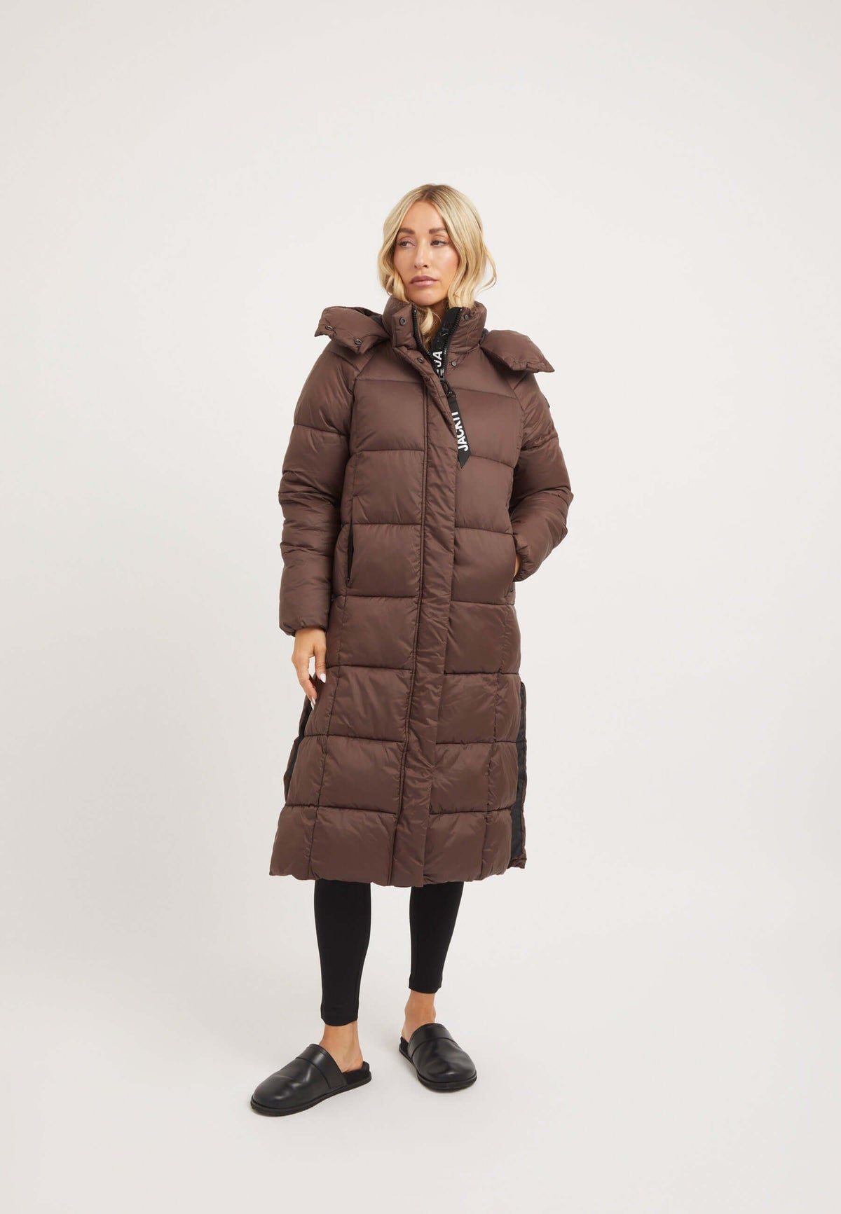 Model wearing Cloud Boss Coat in mid brown, showcasing a womens long puffer coat with a full length silhouette.