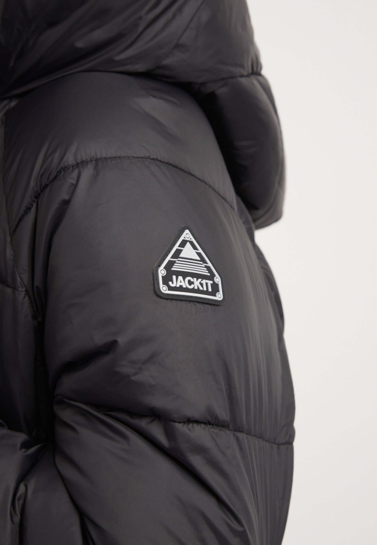 Close-up of the Cloud Boss Coat Black showcasing the reflective badge for a stylish womens long puffer coat.