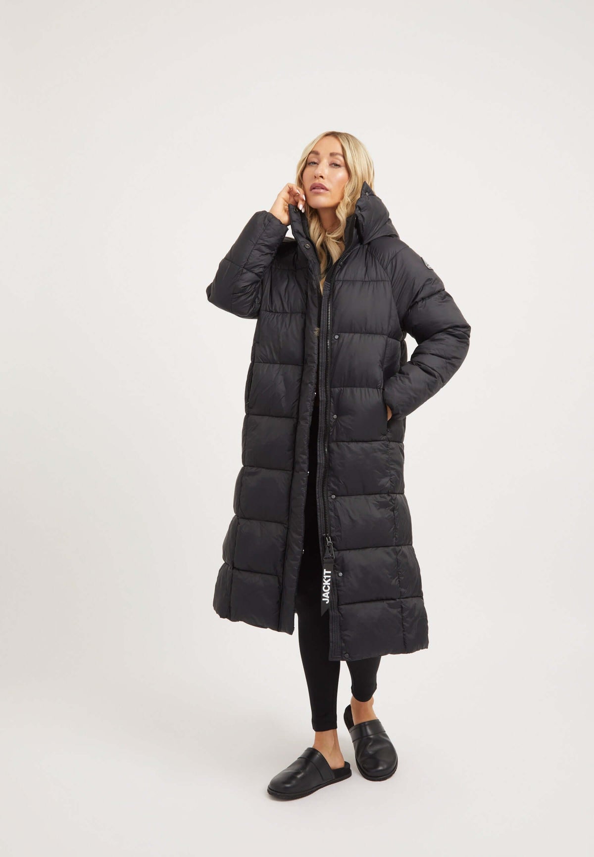Model wearing the womens long puffer coat in black, showcasing its full-length silhouette and removable hood.