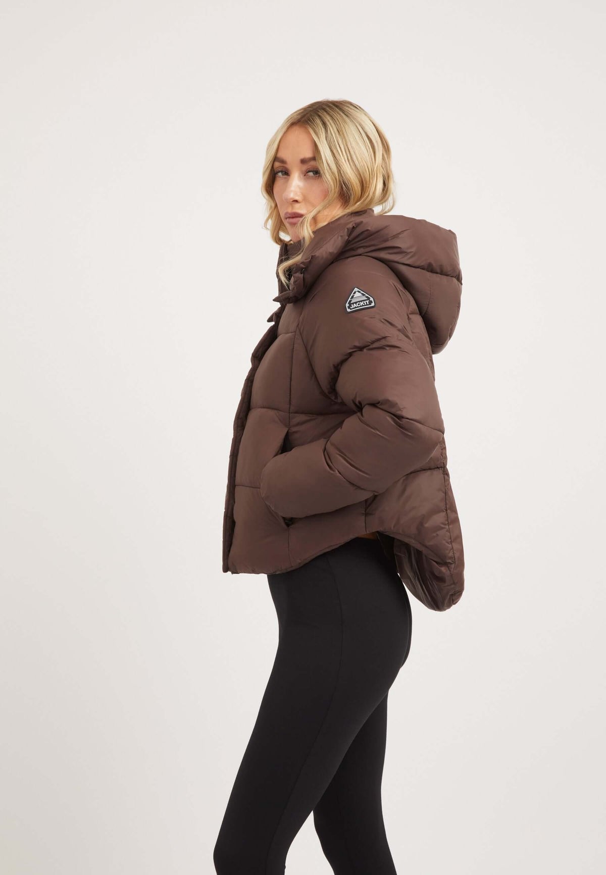 Woman wearing Cloud Crop Jacket Mid Brown, showcasing short puffer jacket women style with a modern silhouette.