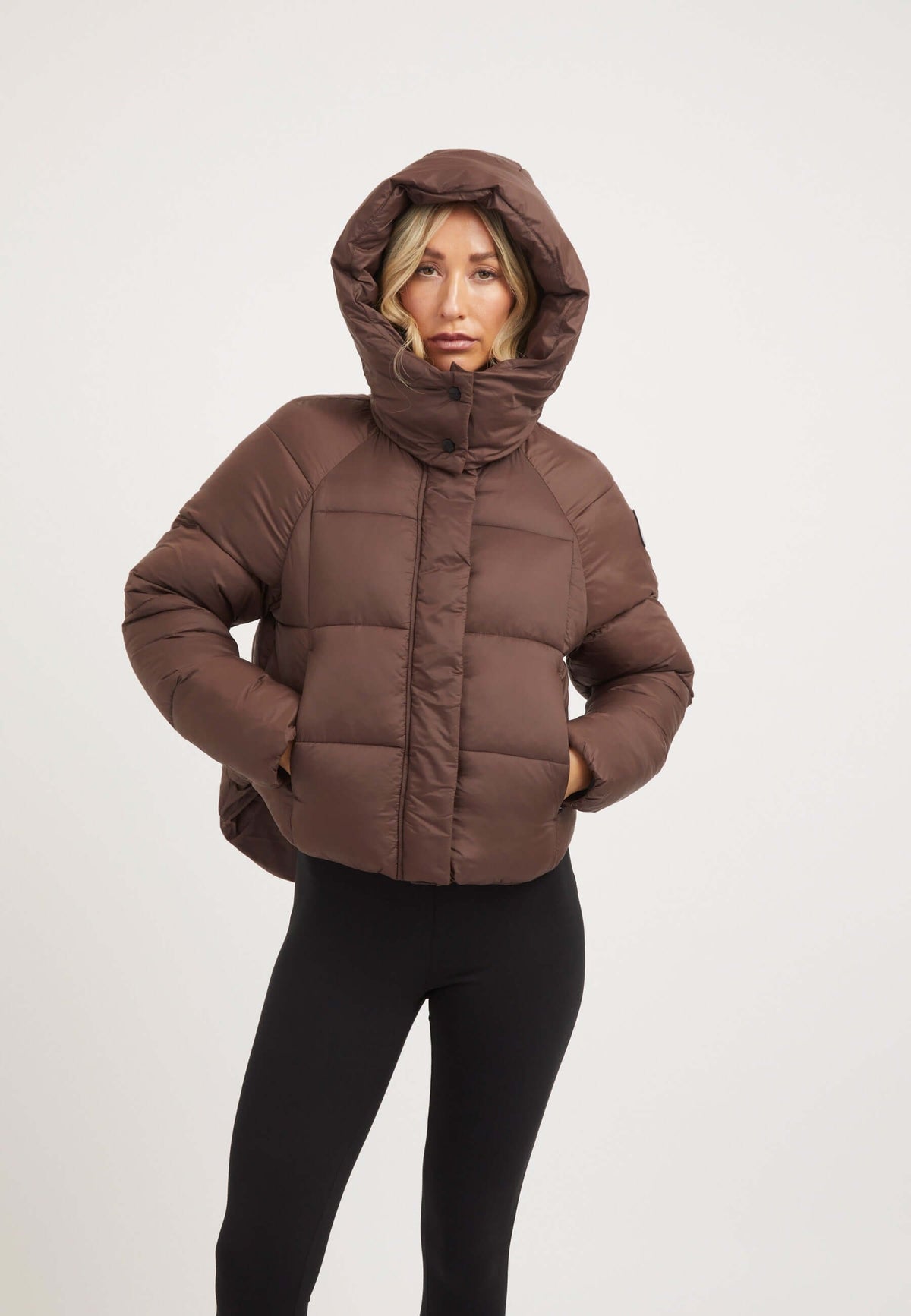 Short puffer jacket women in mid brown color, featuring a cropped cut and adjustable hood for modern style.