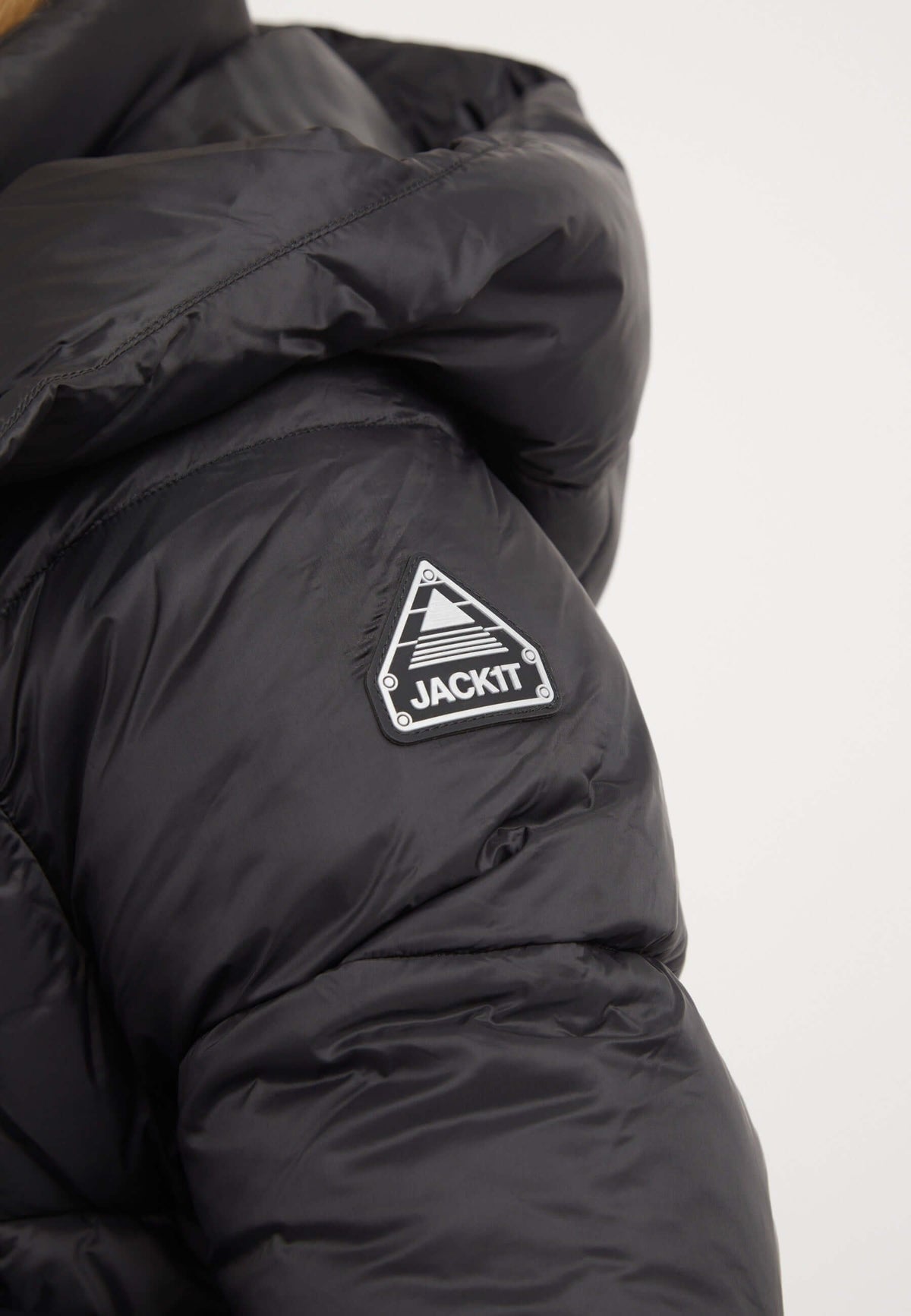 Close-up of Cloud Crop Jacket Black showing reflective badge, part of the stylish womens short puffer jacket collection.