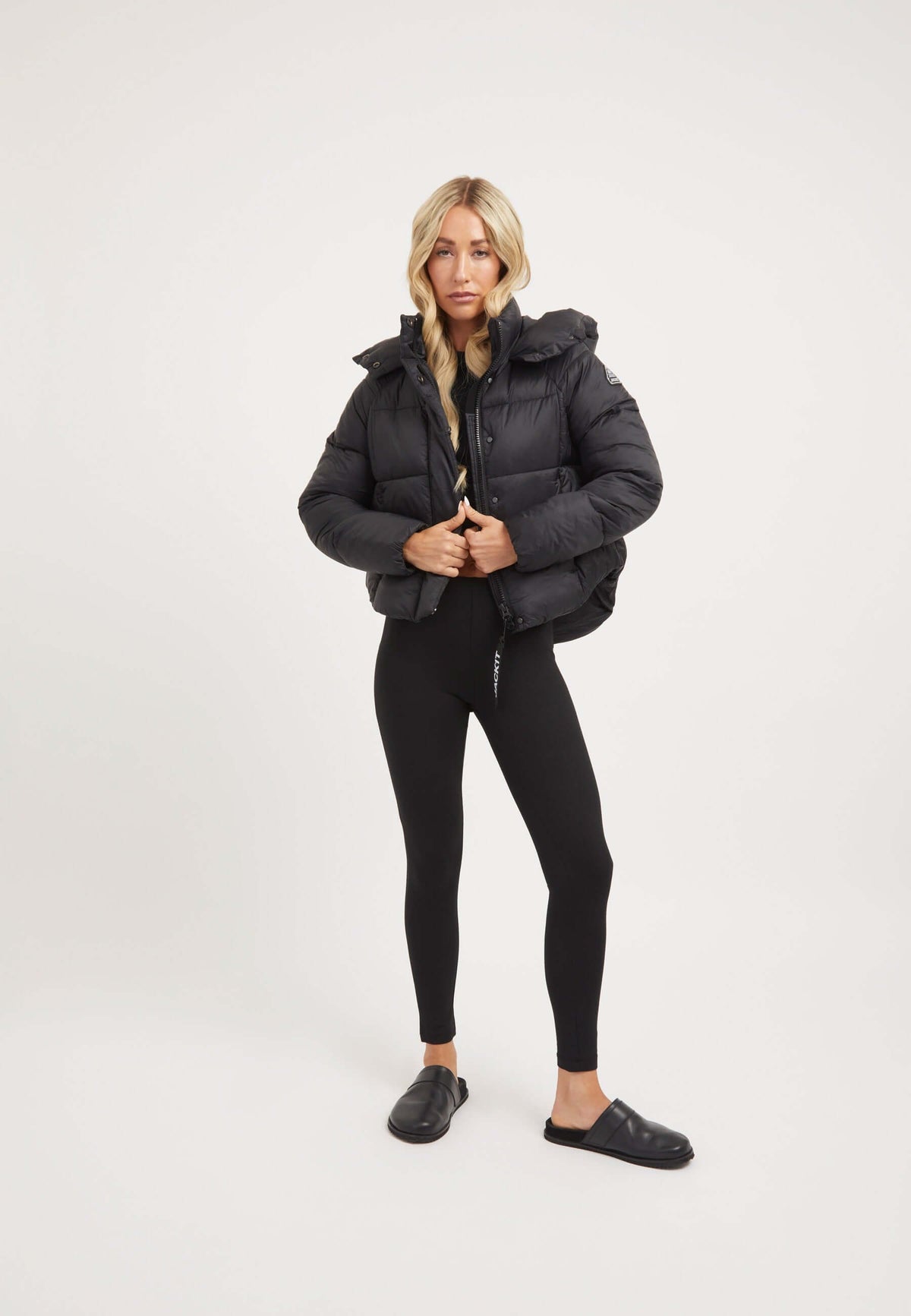 Wearing a stylish Cloud Crop Jacket Black, a womens short puffer jacket, paired with black leggings and casual shoes.