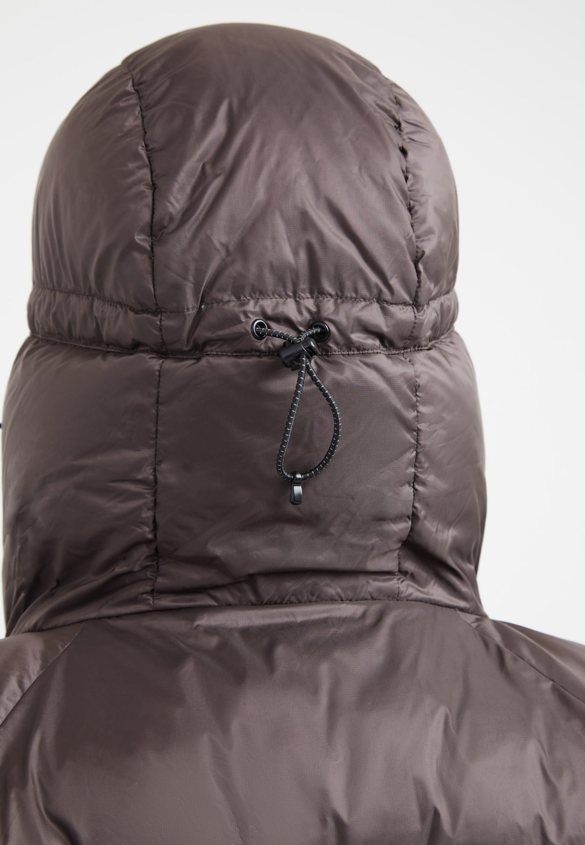 Back view of oversized puffer brown jacket with adjustable hood and durable fabric.