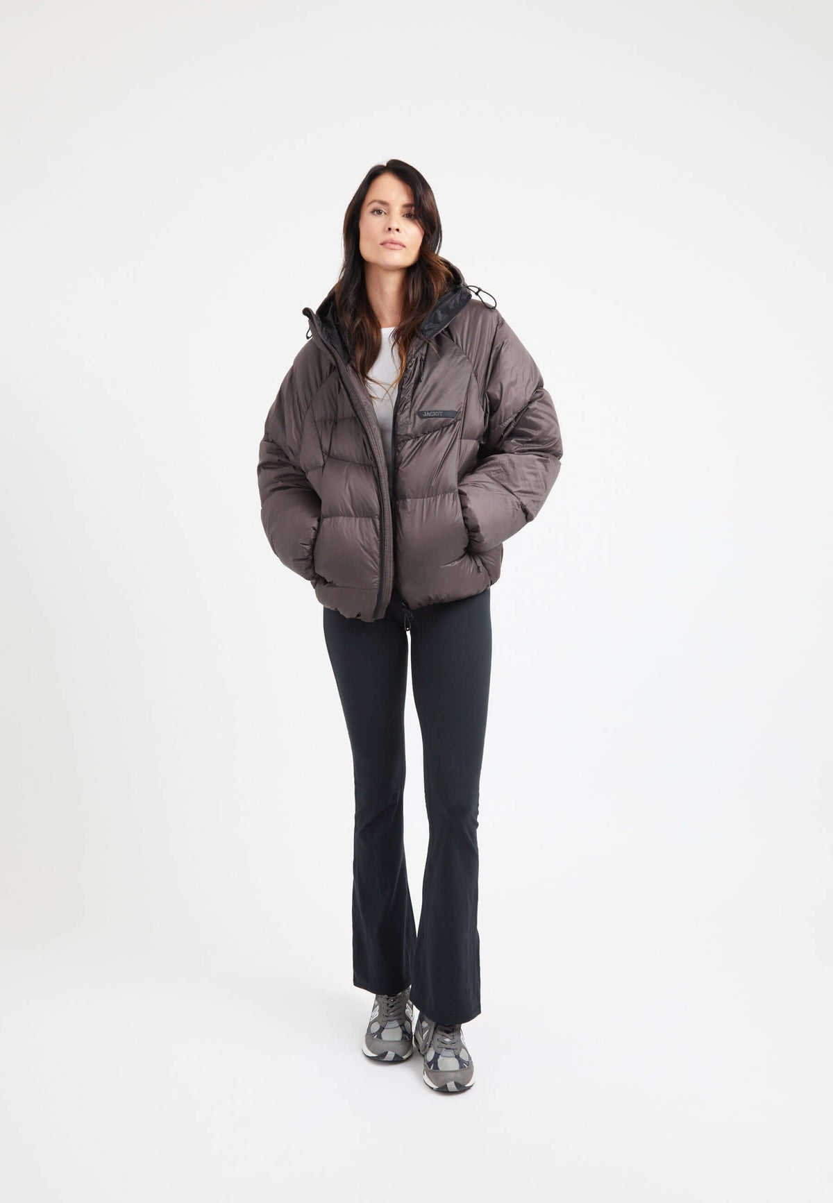 Model wearing oversized puffer brown jacket with adjustable hood and fleece lined pockets.