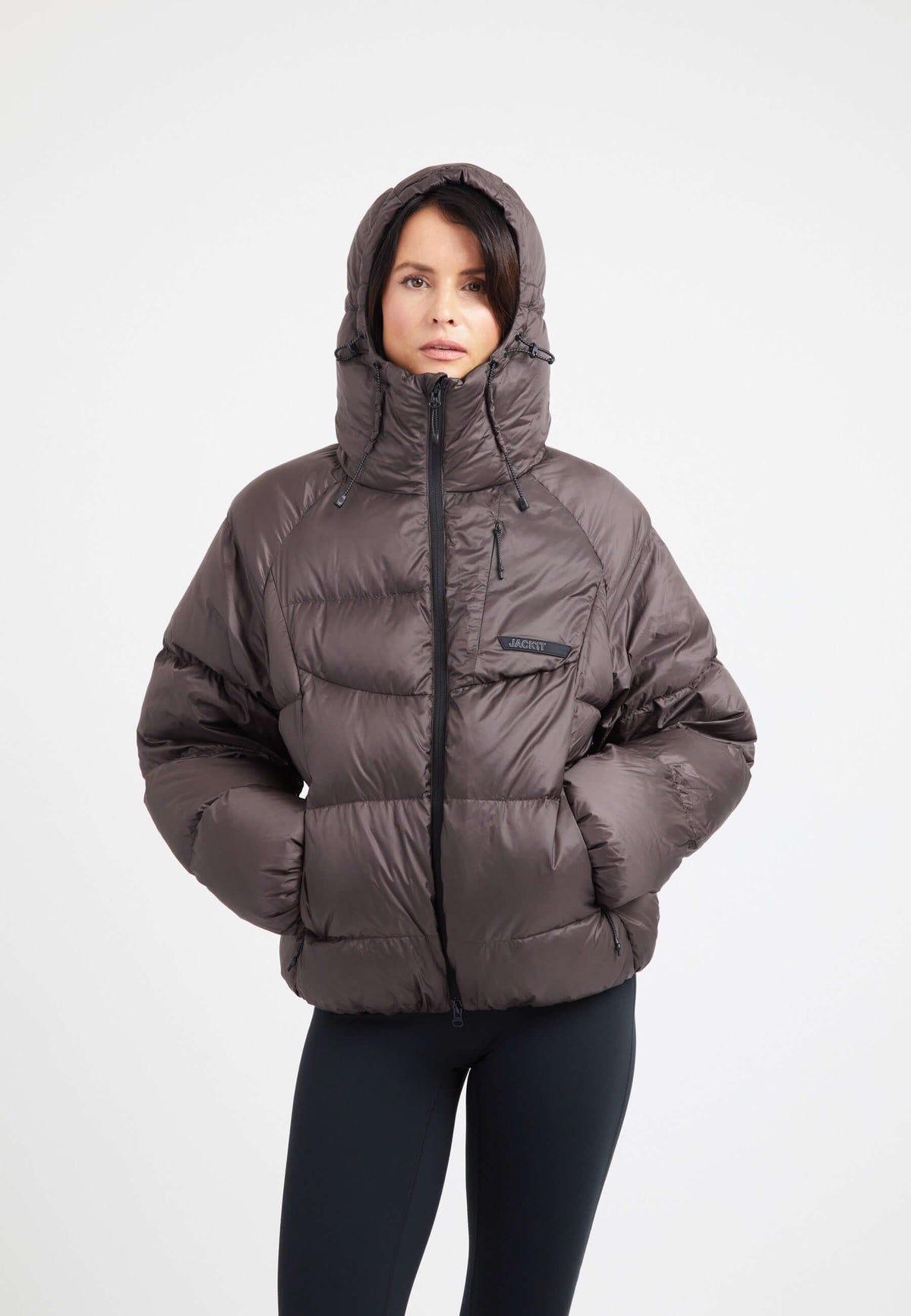 Model wearing an oversized puffer brown jacket with a hood, showcasing a modern design and RDS certified down fill.