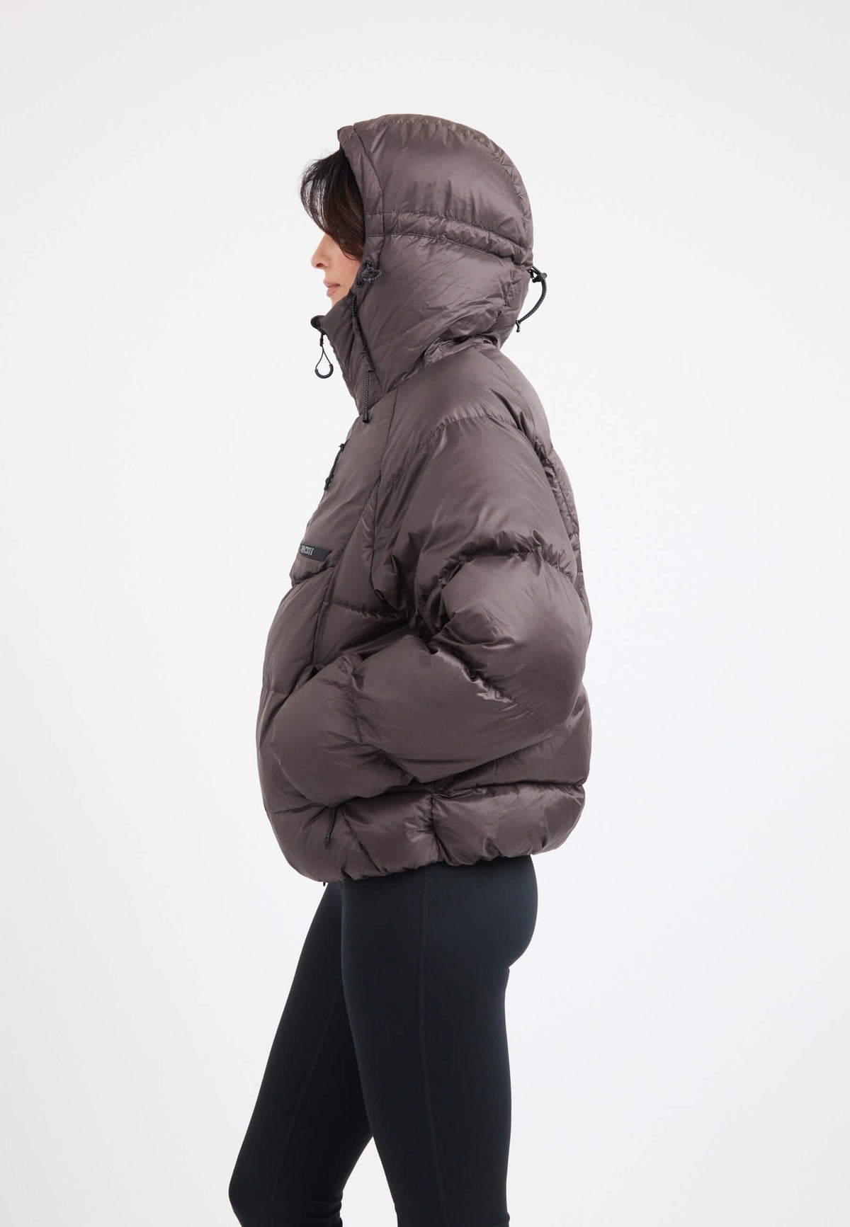 Side view of an oversized puffer brown jacket with an adjustable hood and dark fabric, ideal for winter wear.