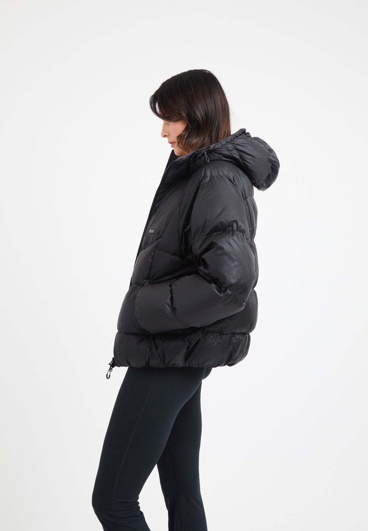 Model wearing an oversized puffer black jacket with a hood, showcasing its stylish design and features.