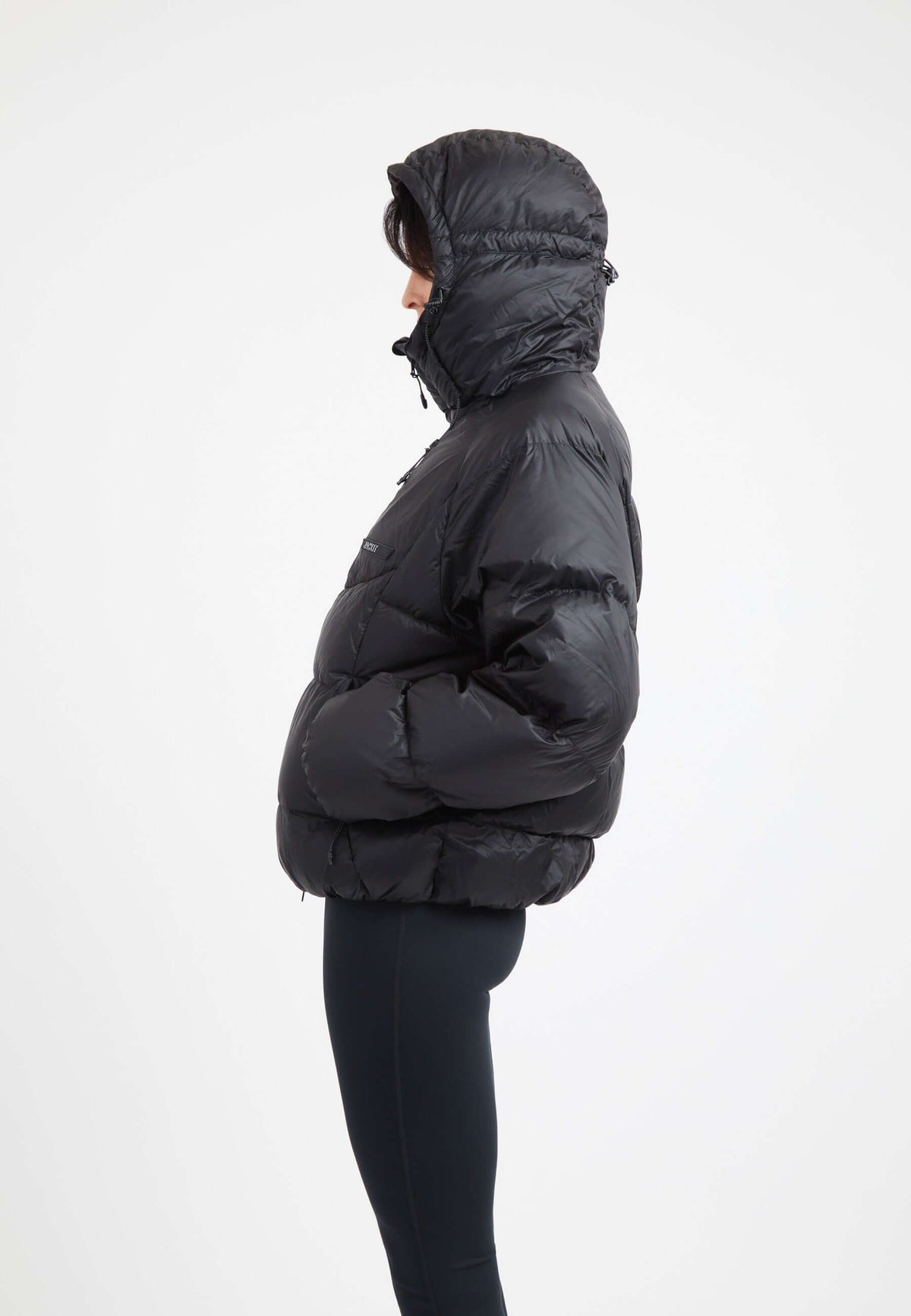 Model wearing an oversized puffer black jacket with an adjustable hood and fleece lined pockets.