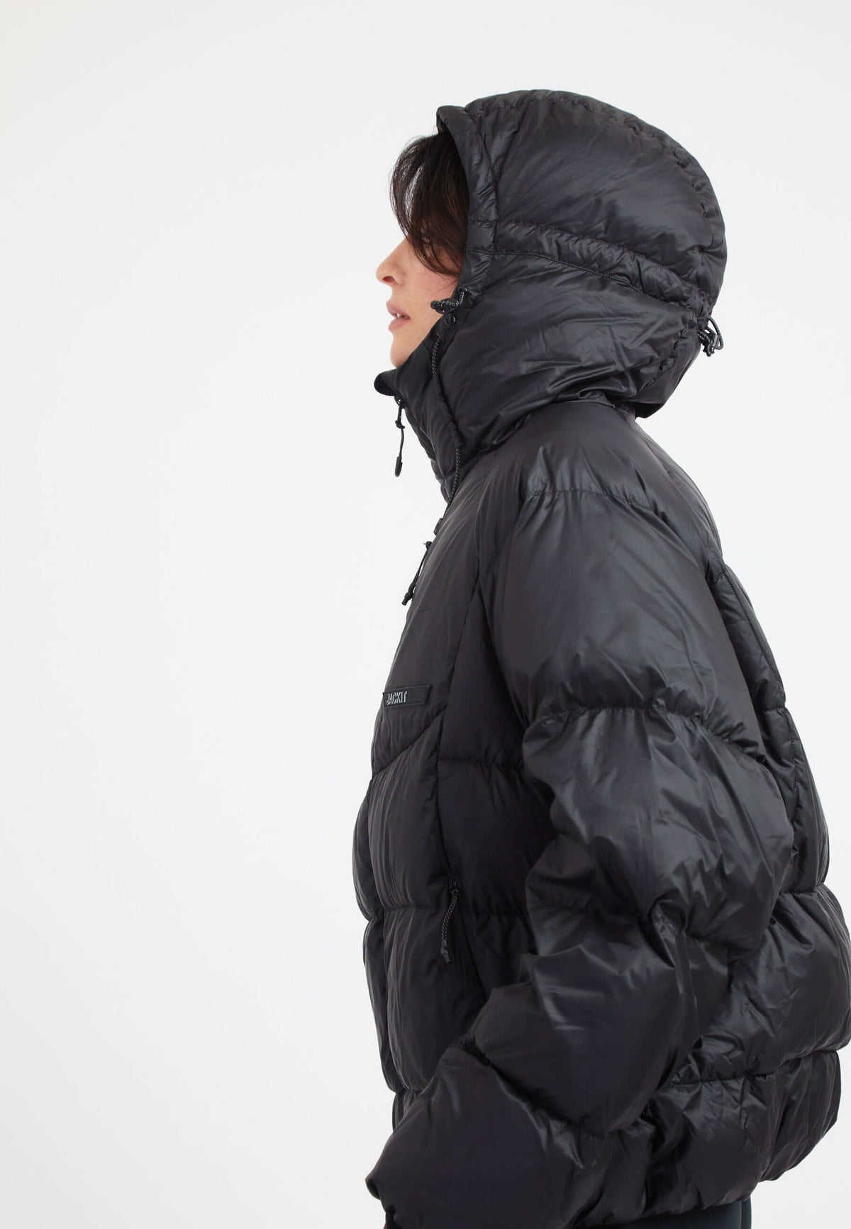 Modern oversized puffer black jacket with adjustable hood and fabric storm cuffs.