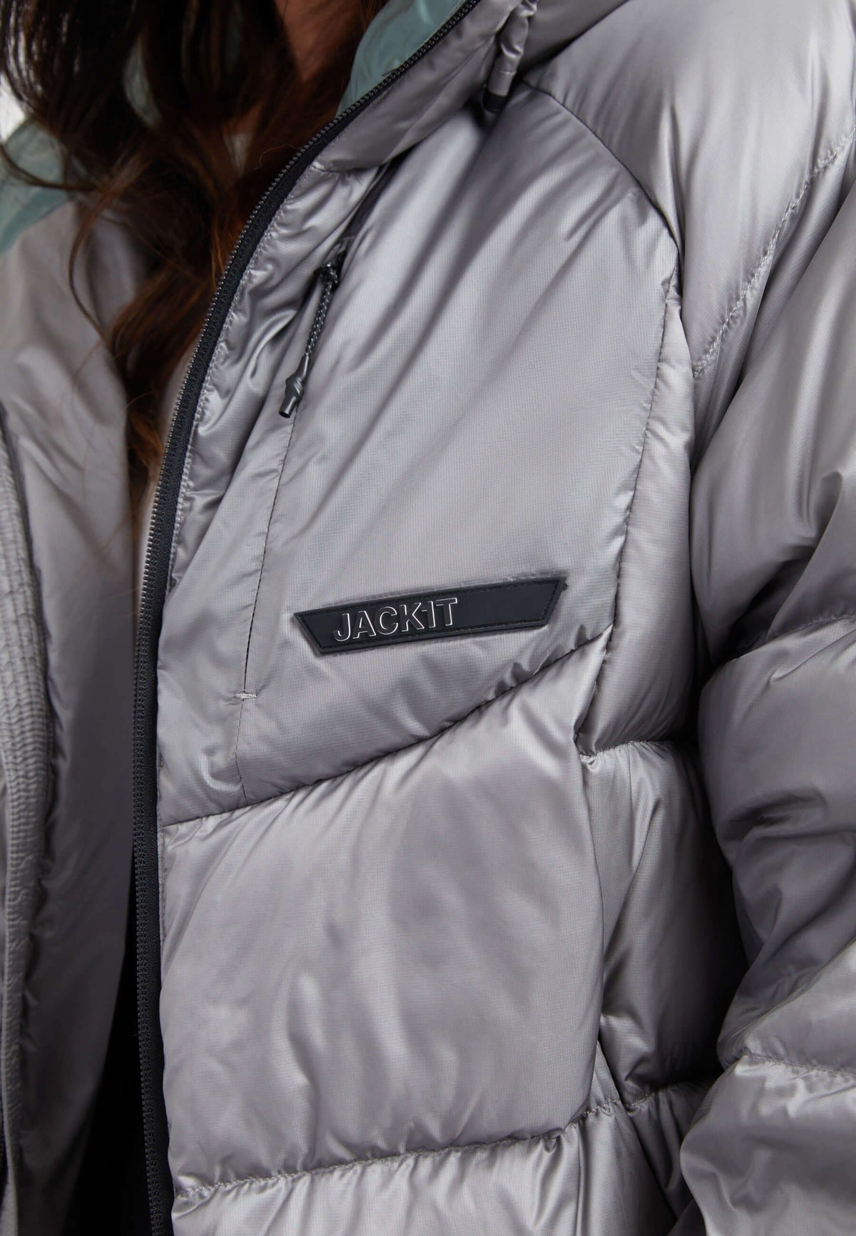 Close-up of a stylish oversized puffer grey jacket featuring a Jackit logo and modern design.