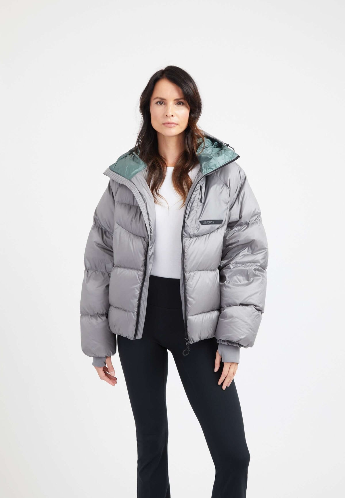 Model wearing an oversized puffer grey jacket with adjustable hood and fleece lined pockets.