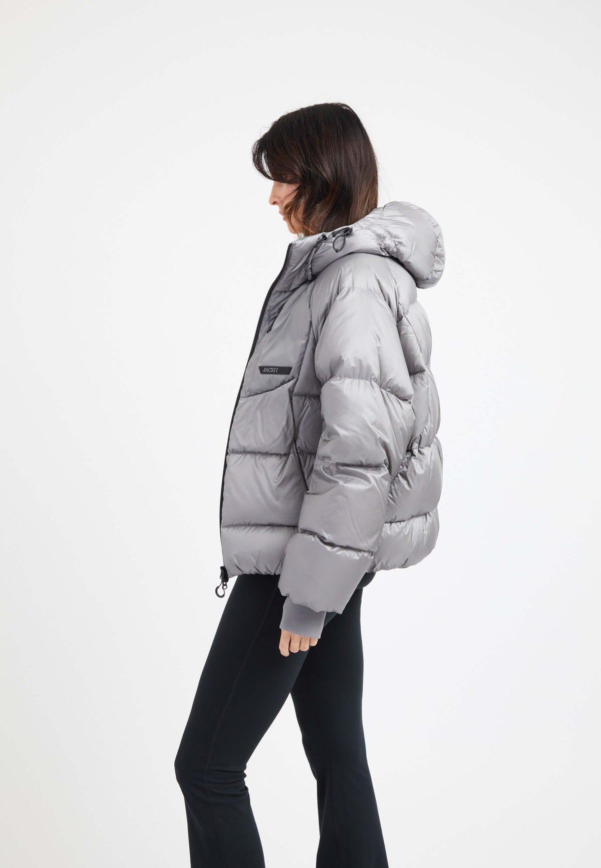 Model wearing an oversized puffer grey jacket with a hood and stylish silhouette.