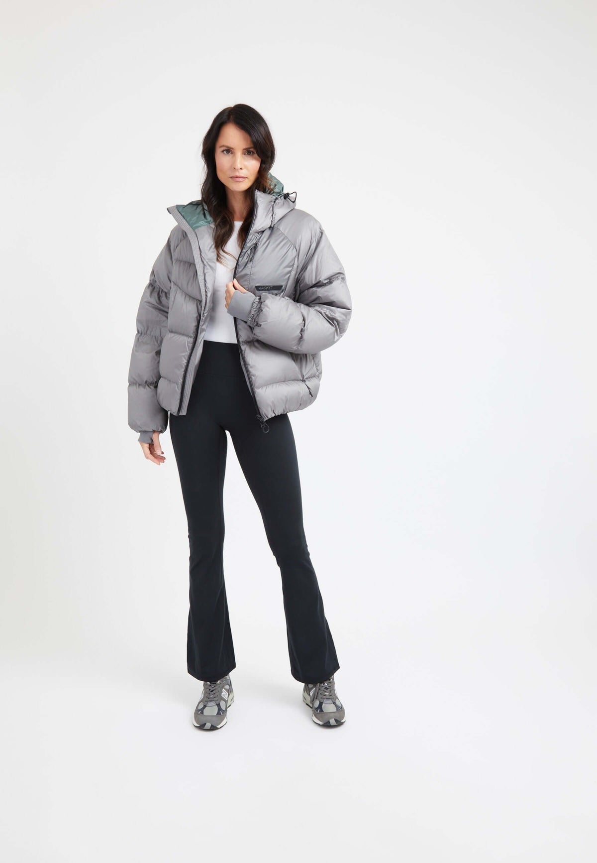Model wearing oversized puffer grey jacket with black pants and sporty shoes, showcasing a stylish winter look.