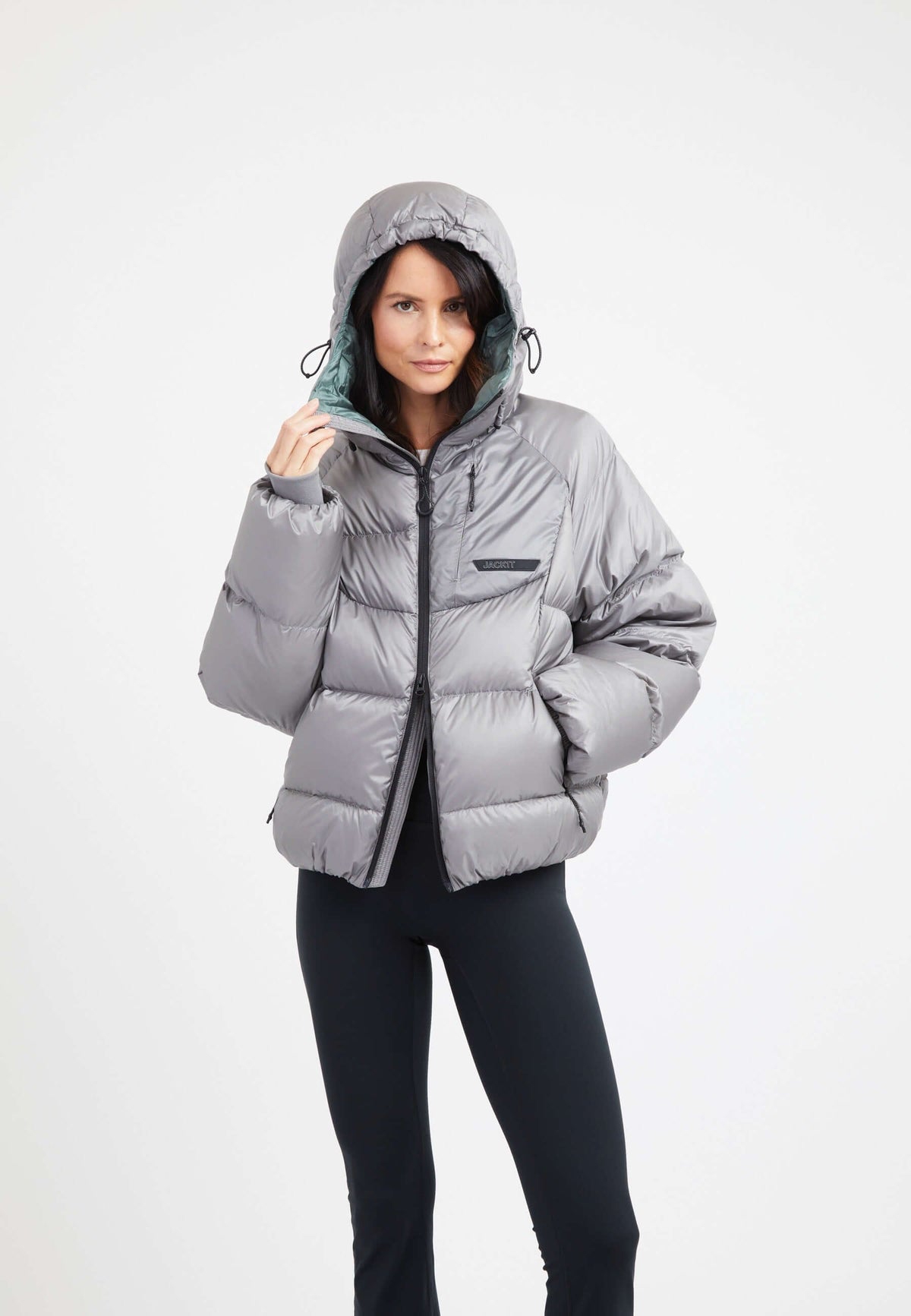 A model wearing an oversized puffer grey jacket, showcasing its stylish design and adjustable hood.