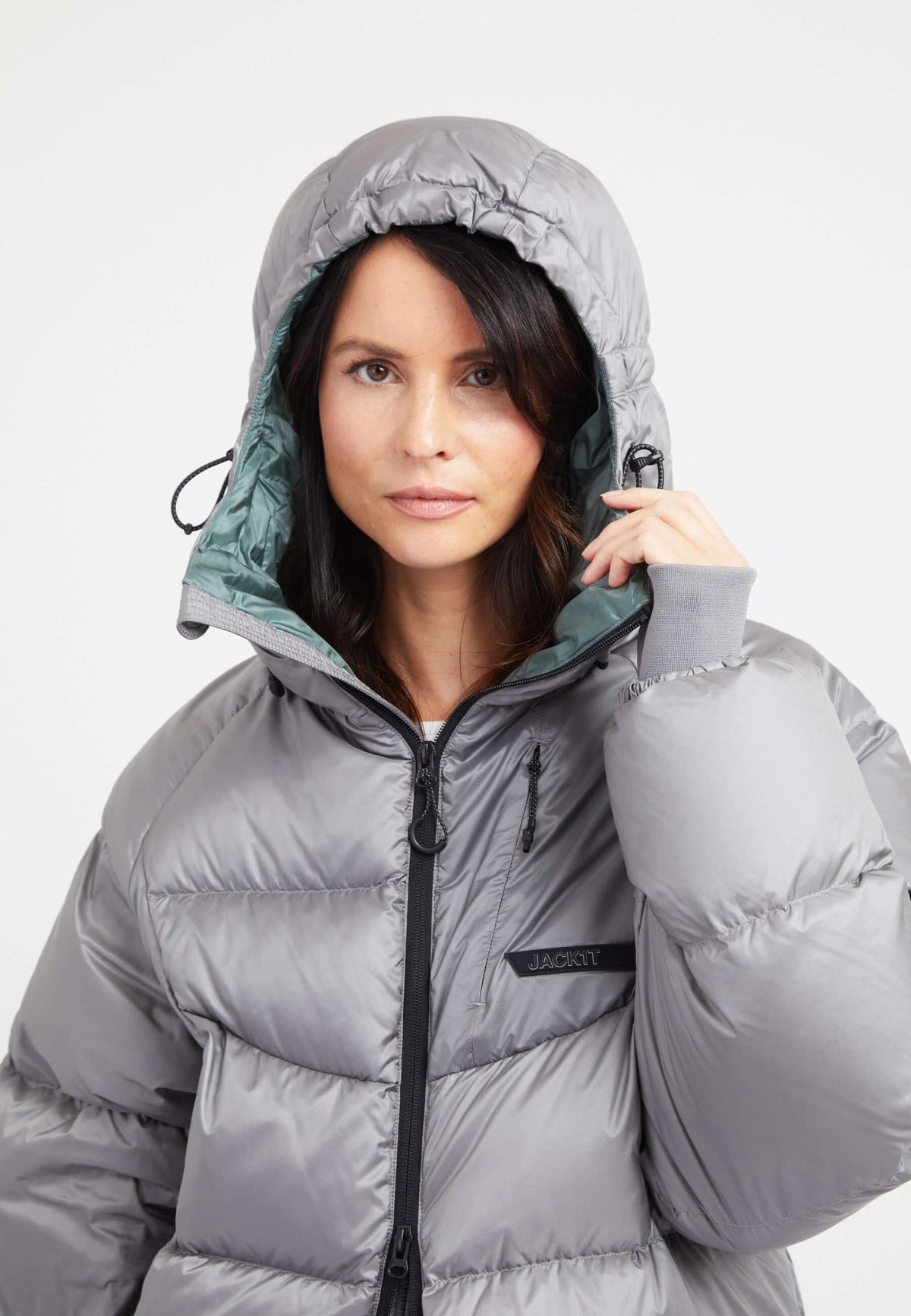Model wearing an oversized puffer grey jacket with an adjustable hood and fleece-lined hand pockets.
