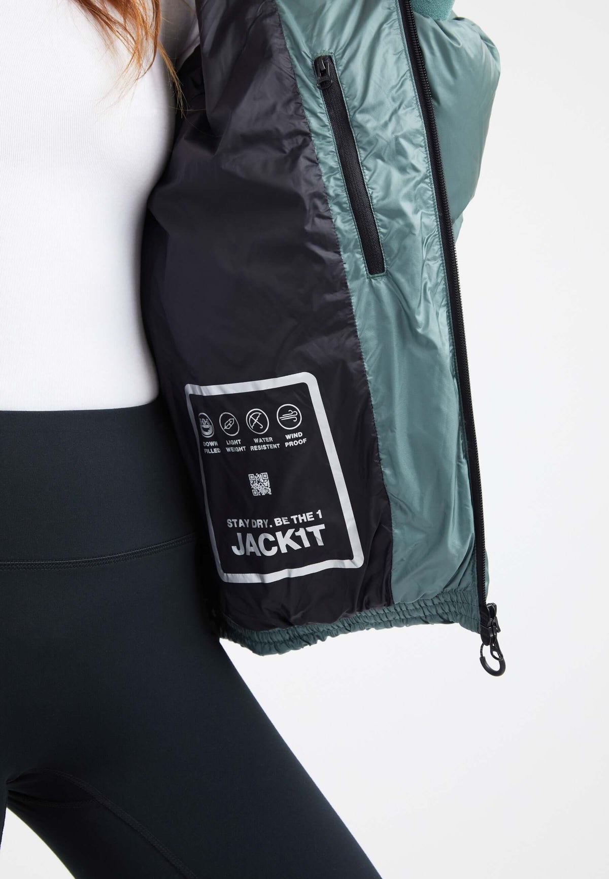 Inside view of an oversized puffer green jacket, showing care label and zipper details on a model.
