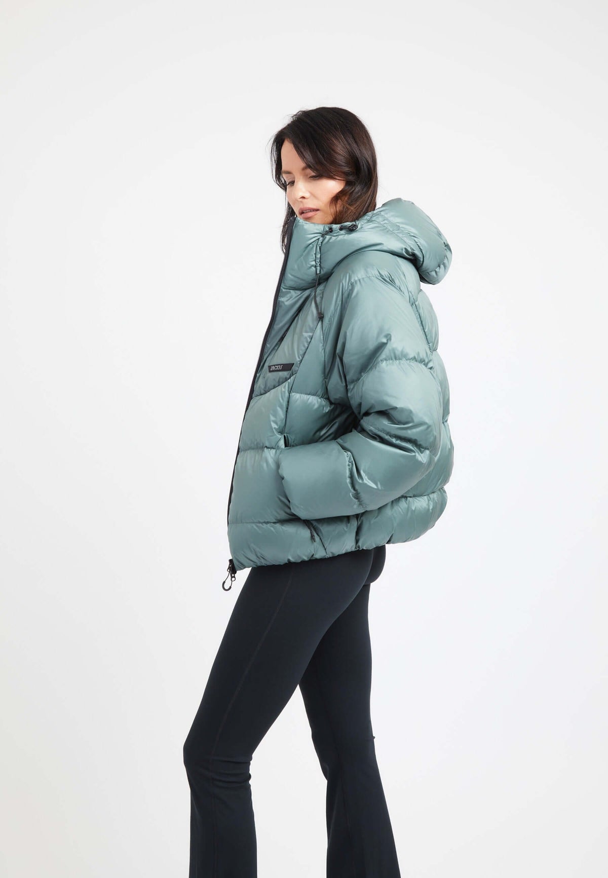 Stylish model wearing an oversized puffer green jacket with a hood and sleek design.