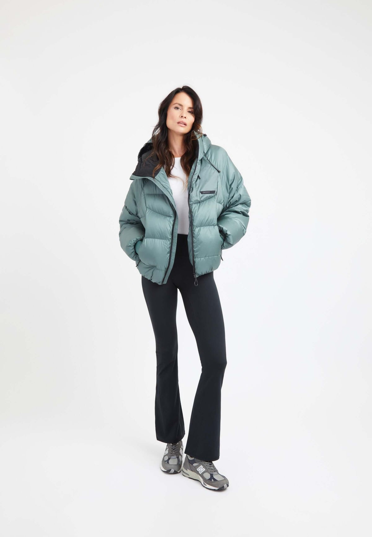 Model wearing an oversized puffer green bubble jacket with adjustable hood and fleece lined pockets.