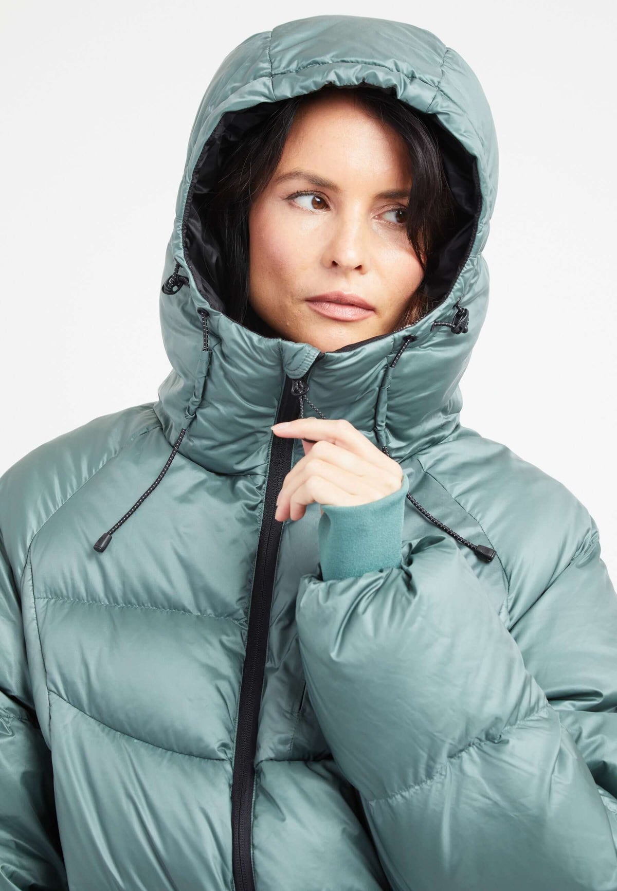 Woman wearing oversized puffer green jacket with adjustable hood, featuring a modern silhouette and cozy design.