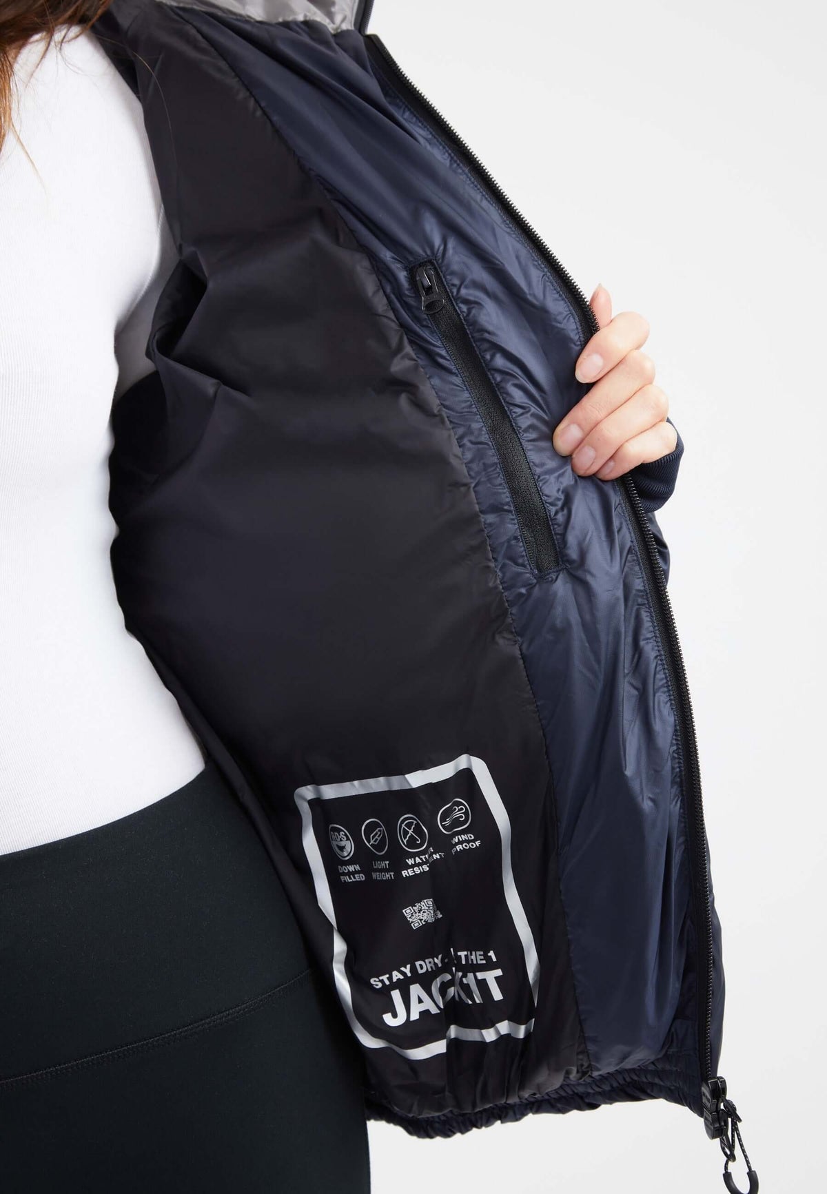 Inside view of oversized puffer navy jacket, showcasing interior pocket and care instructions.