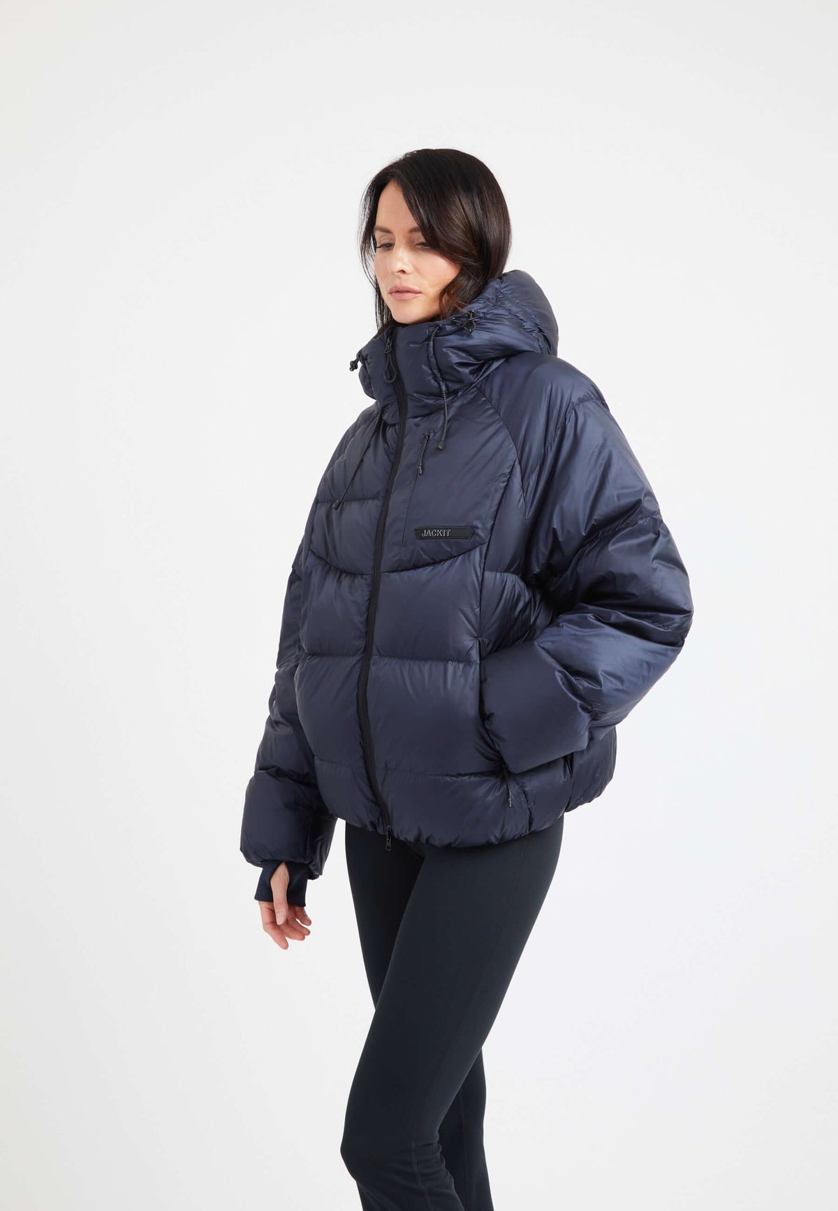 Model wearing an oversized puffer navy jacket featuring adjustable hood and fleece lined pockets.
