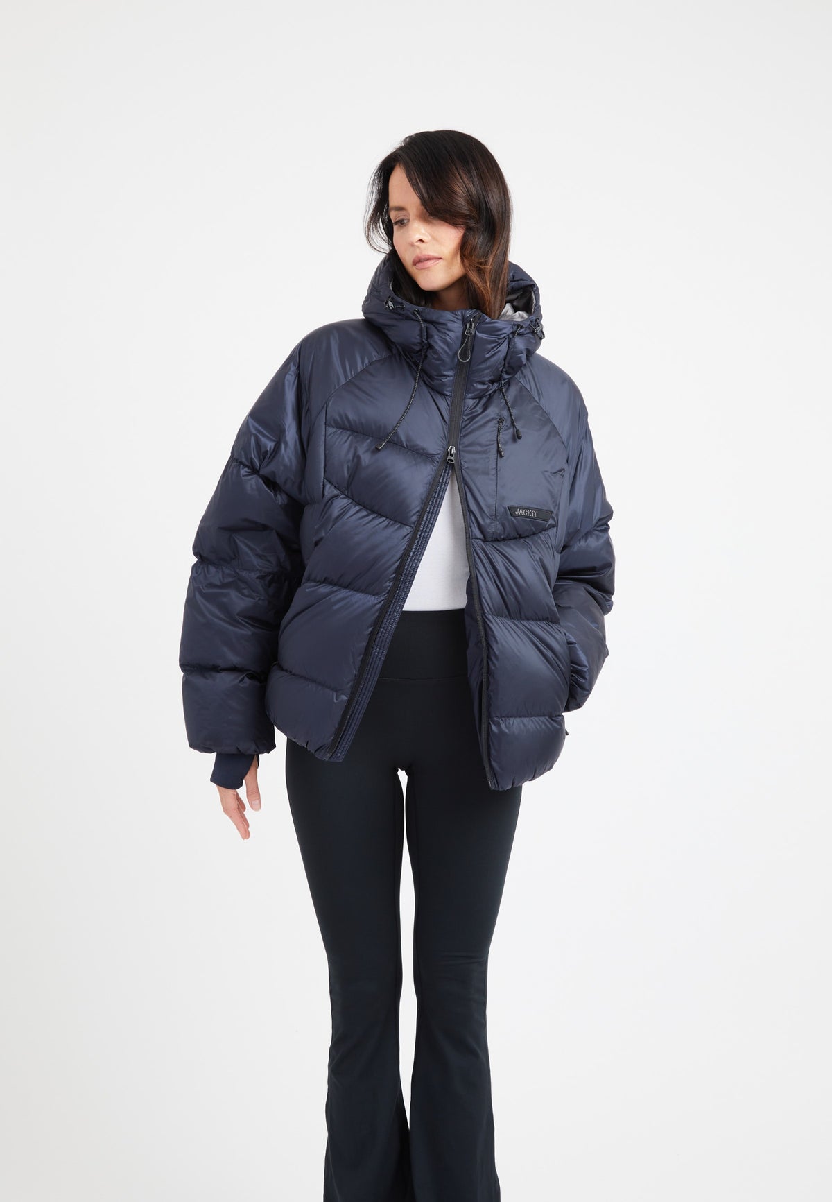 Model wearing an oversized puffer navy jacket with an adjustable hood and fleece lined pockets.