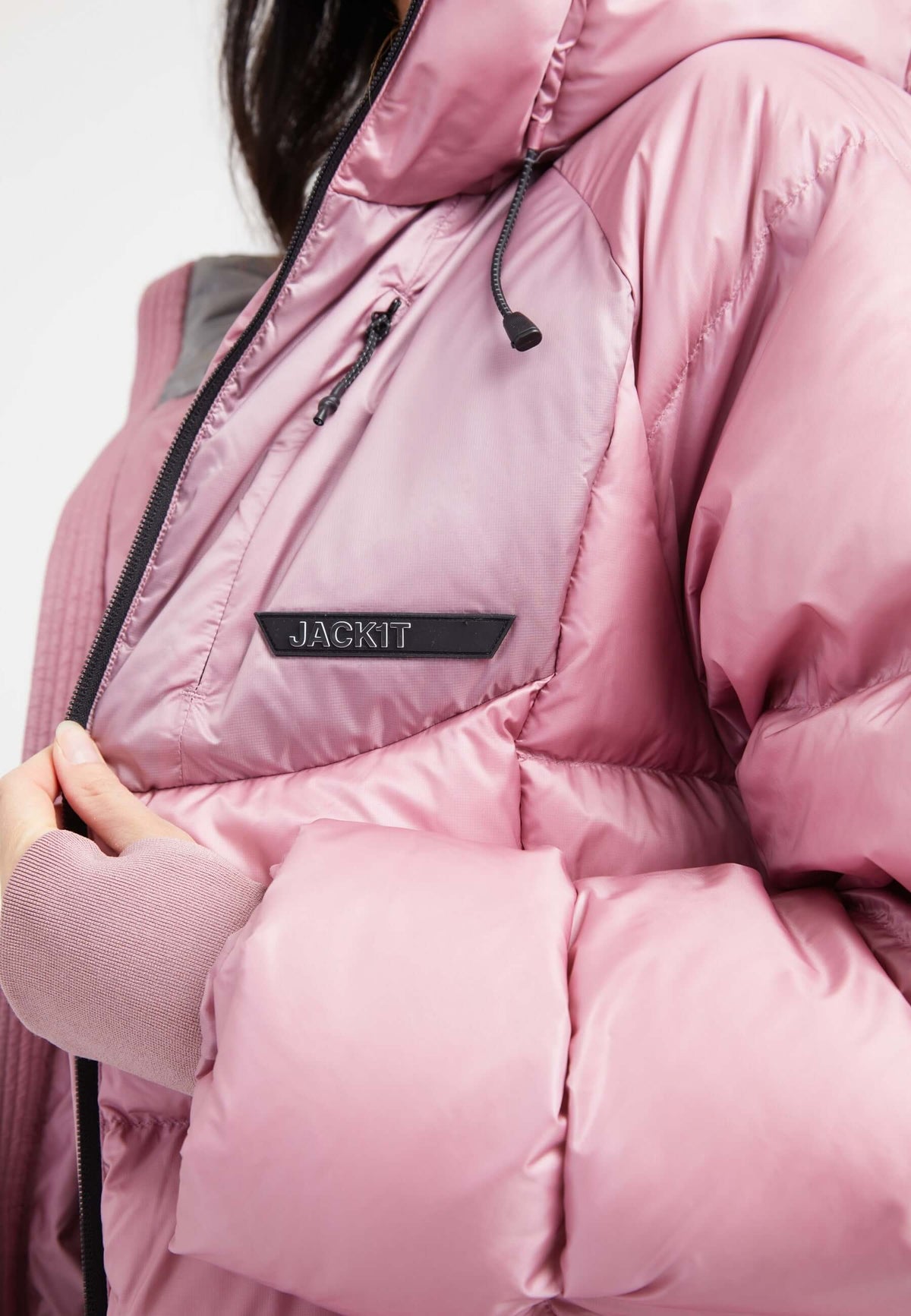 Close-up of a woman wearing a pink oversized puffer jacket with adjustable hood and RDS Certified Down fill.