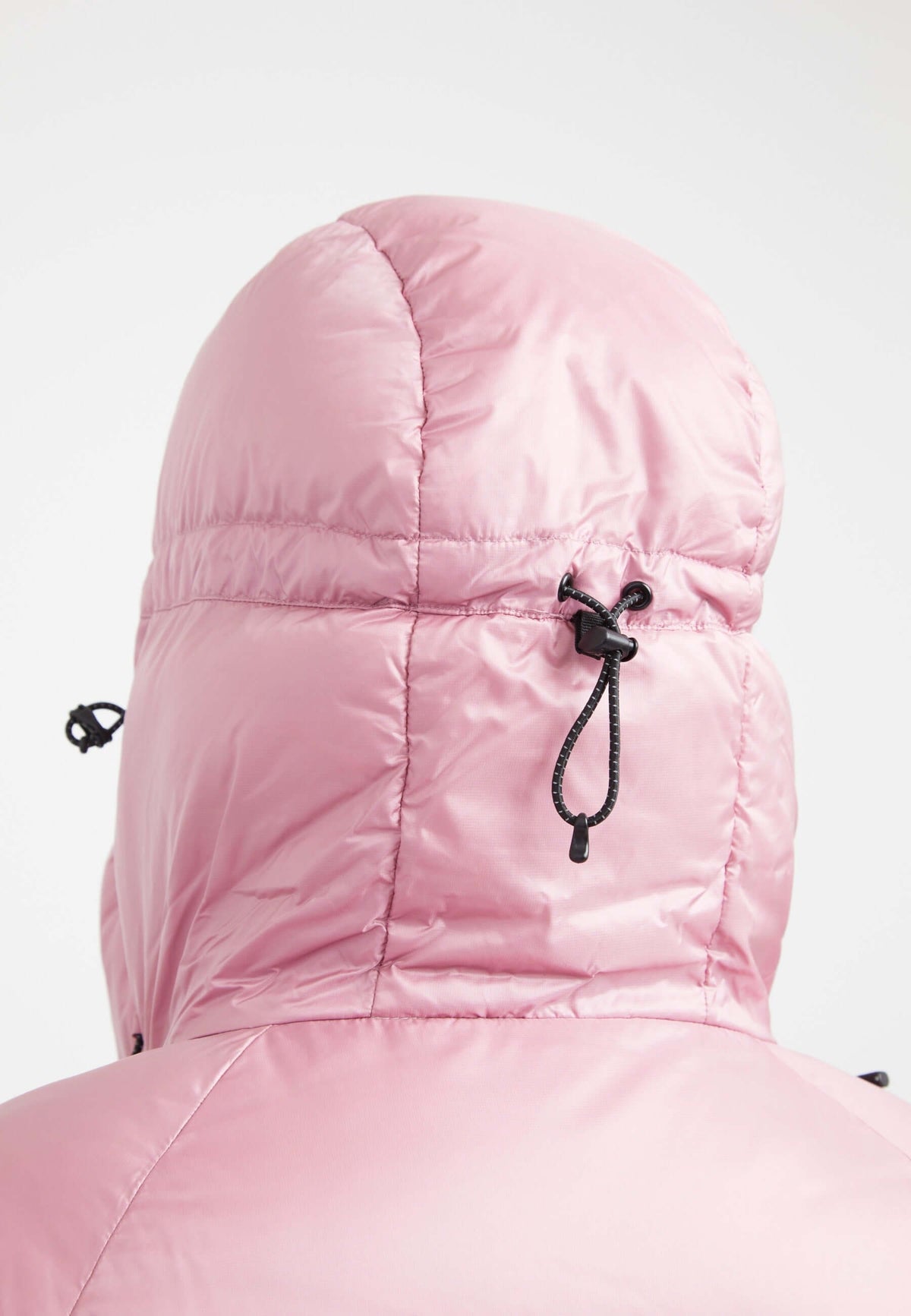 Back view of pink oversized puffer jacket featuring an adjustable hood and fabric storm cuffs.
