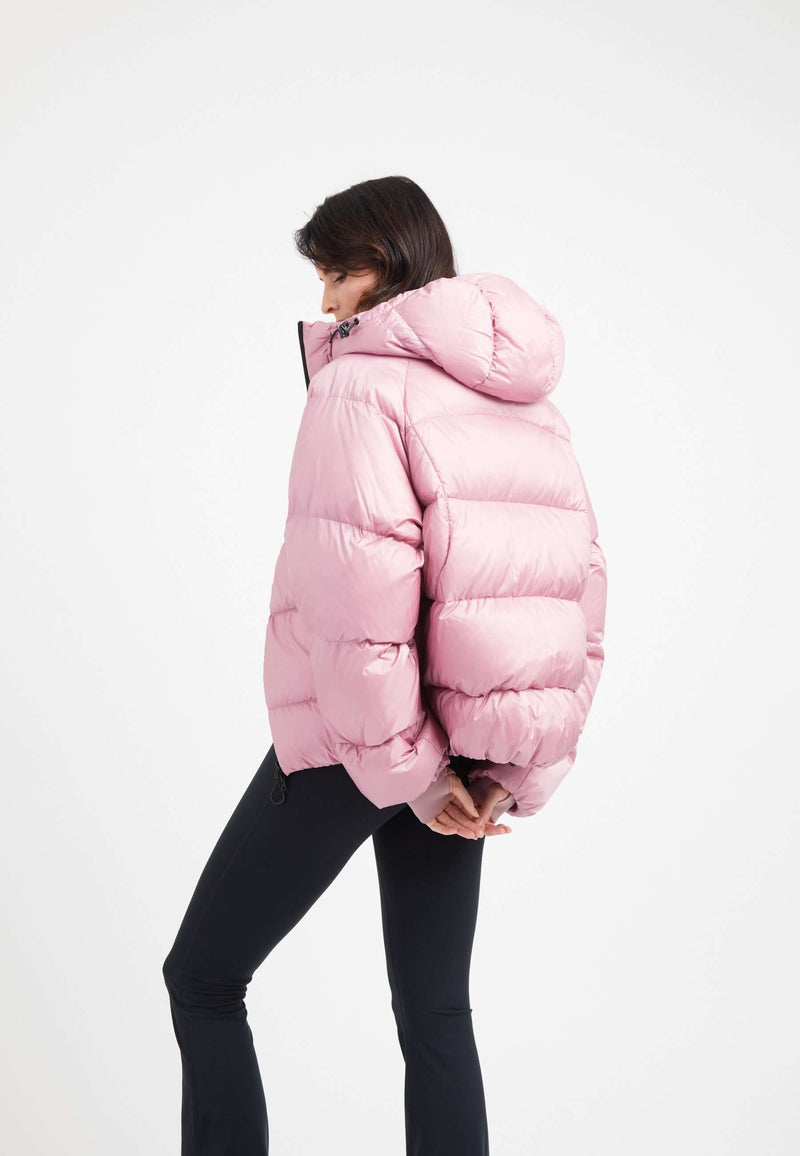 Woman wearing an oversized puffer pink jacket with a hood, showcasing its modern and stylish design.