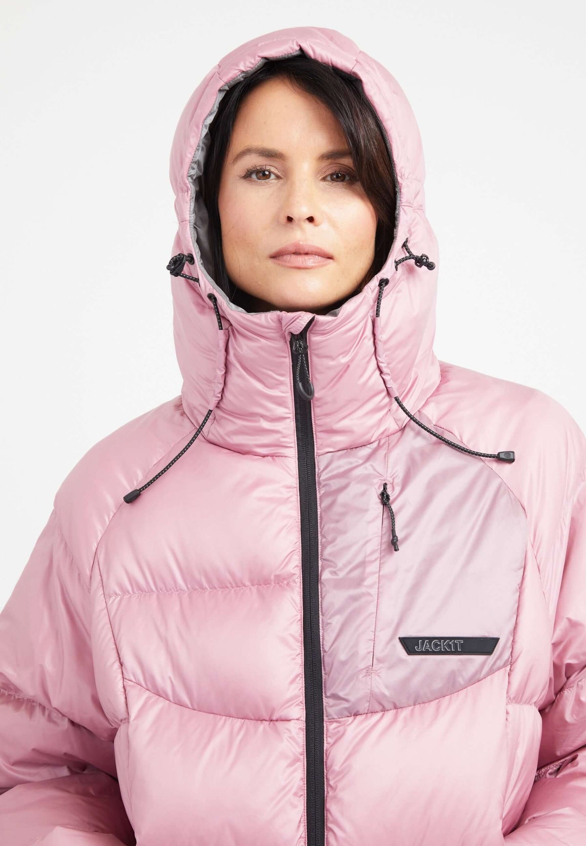Model wearing a pink oversized puffer jacket with an adjustable hood and fleece-lined pockets.