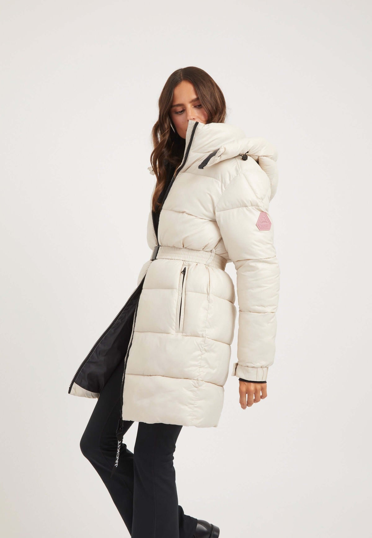 Woman modeling the EZ Belted Coat Stone, a womens belted puffer coat, showcasing its tapered design and removable belt.