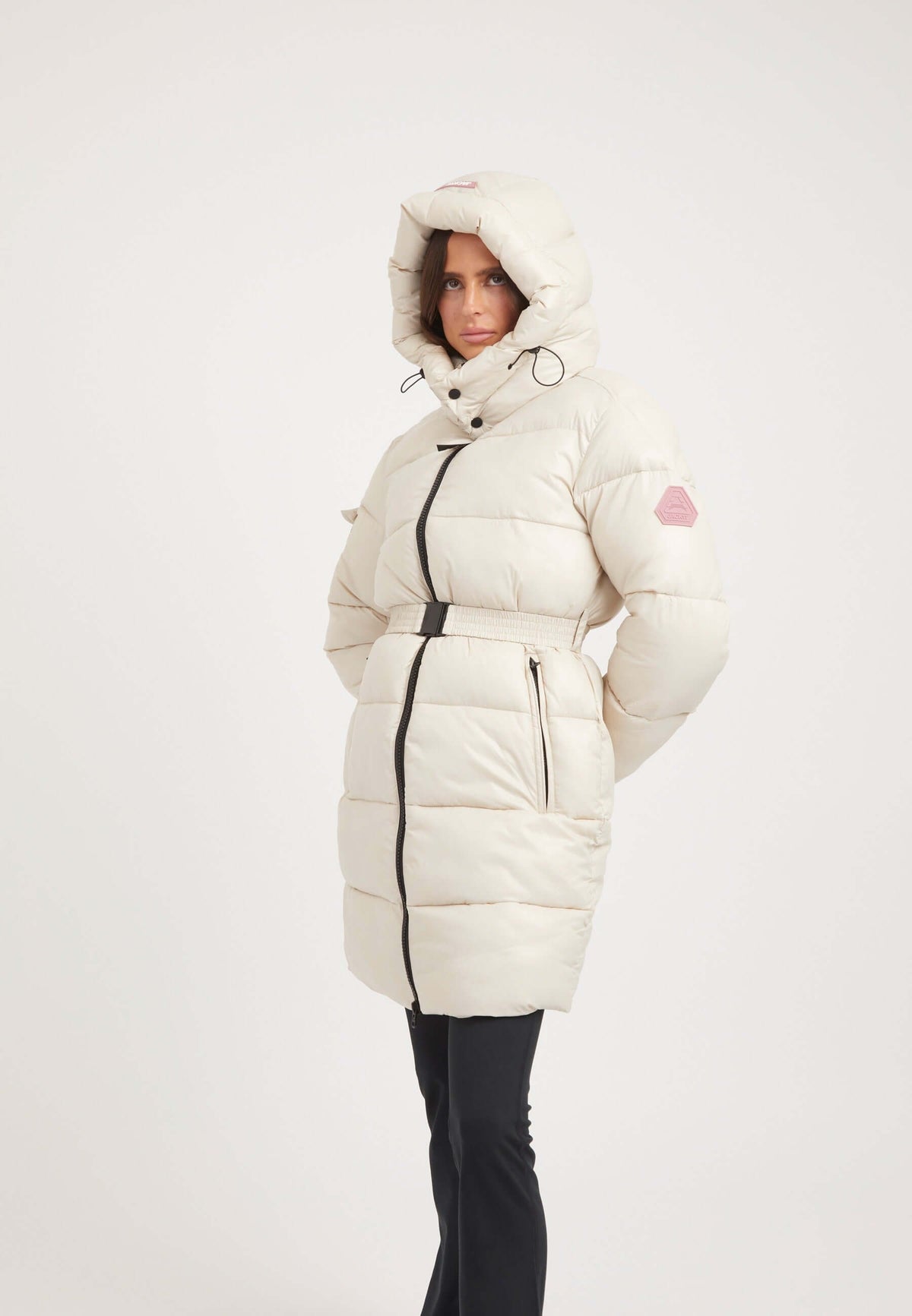 Model wearing an EZ Belted Coat Stone, a womens belted puffer coat with a hood and removable belt.