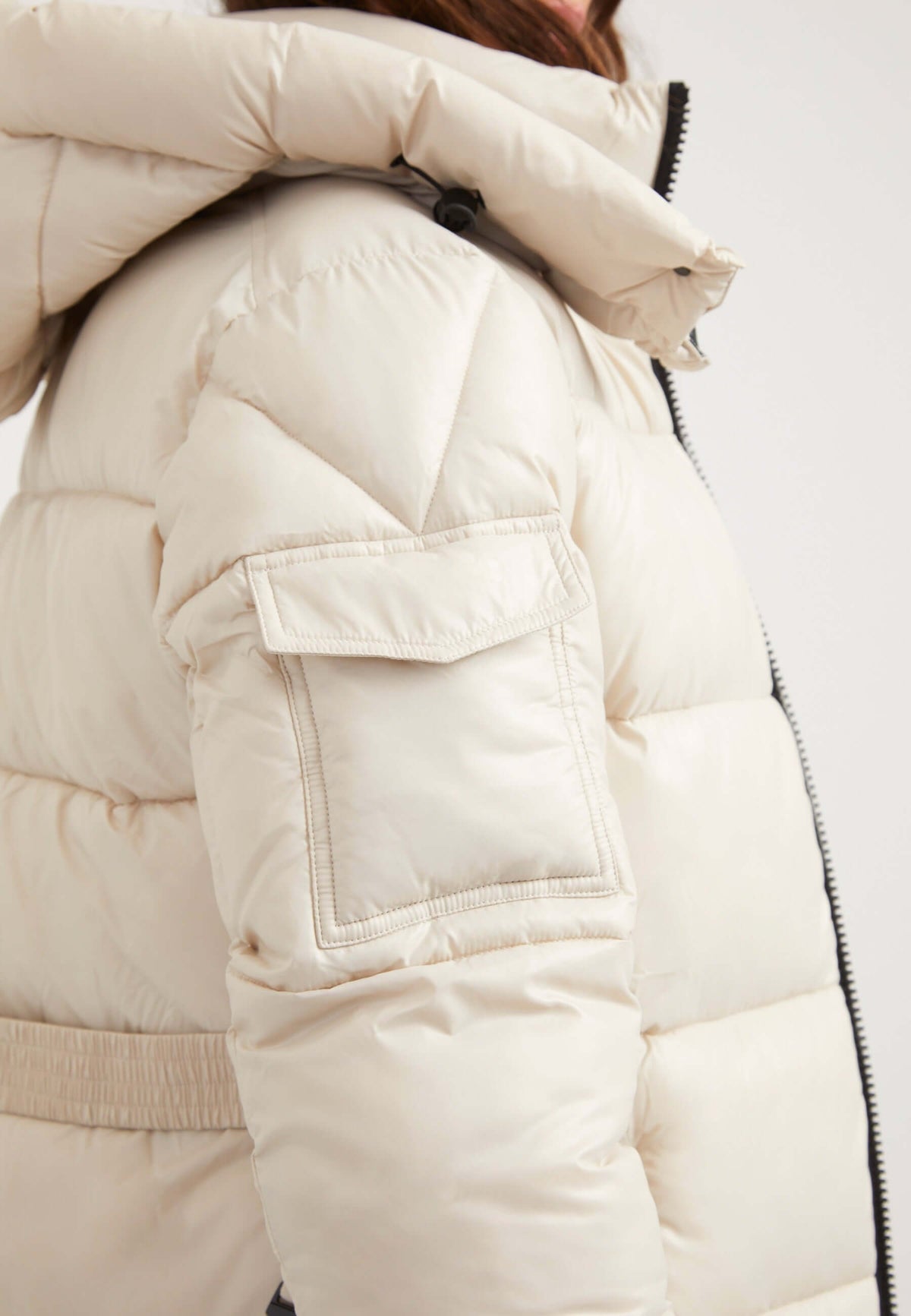 womens belted puffer coat featuring tapered design, removable belt, and a grown-on hood in stone color.