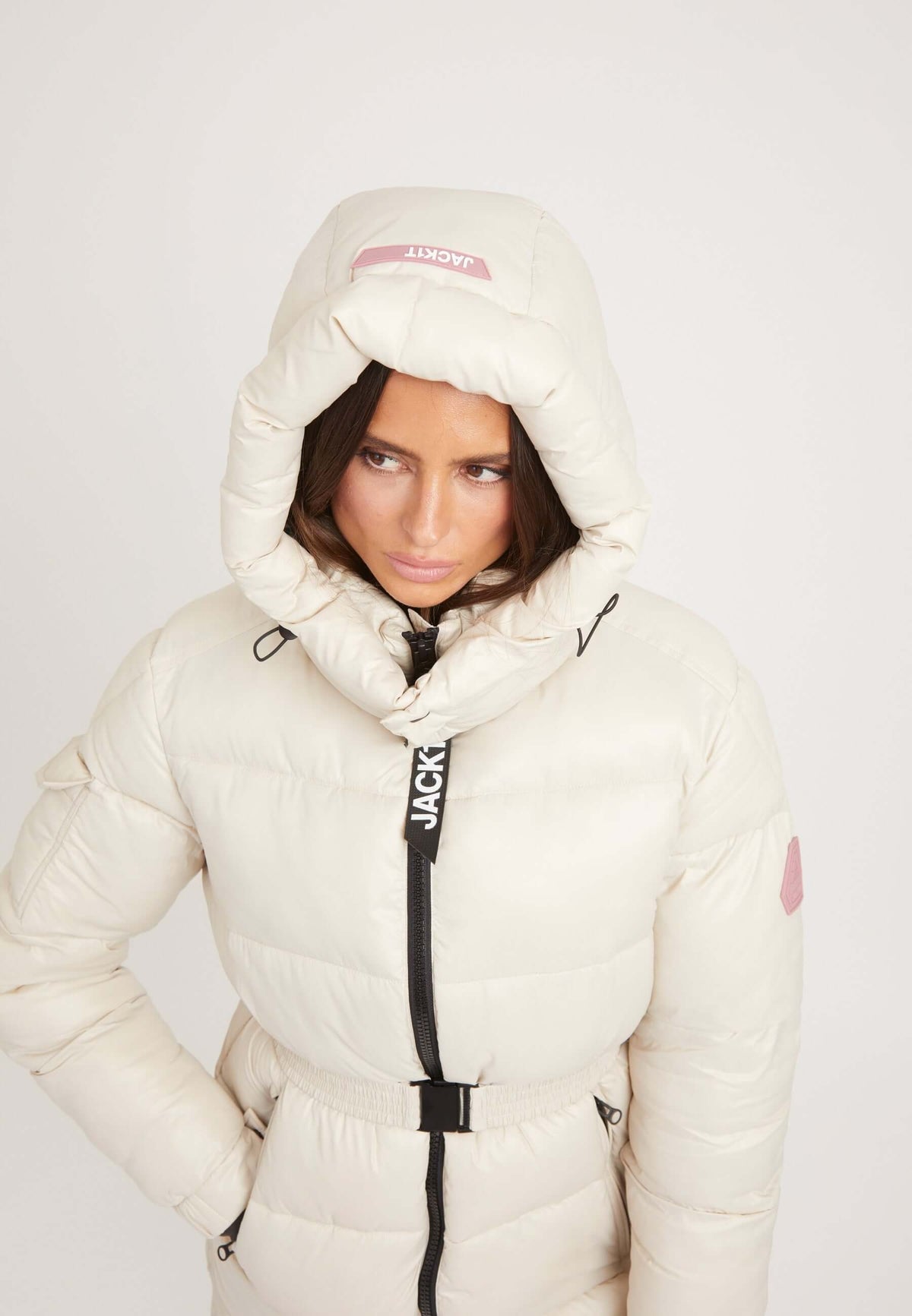 Model wearing EZ Belted Coat Stone, a womens belted puffer coat with a hood and removable belt.