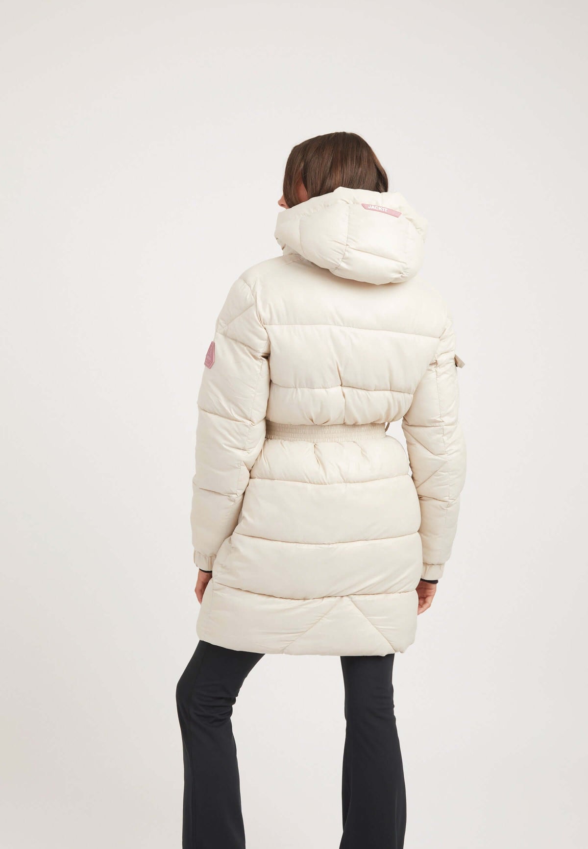 Back view of a woman wearing a stylish EZ Belted Coat Stone, featuring a hood and puffer design, ideal for cold weather.