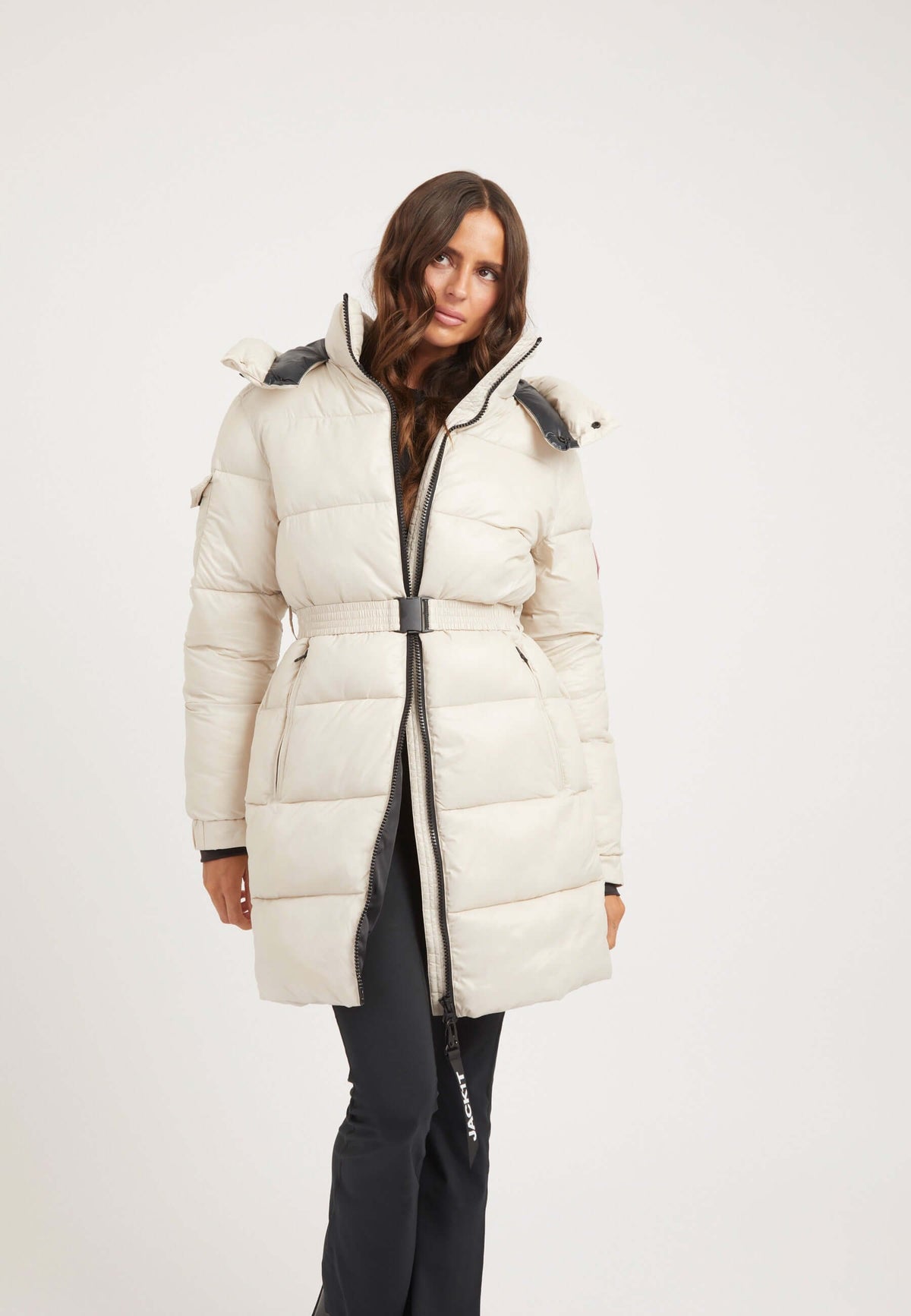 Womens belted puffer coat in stone color, featuring a removable belt, hood, and tapered design, perfect for winter.