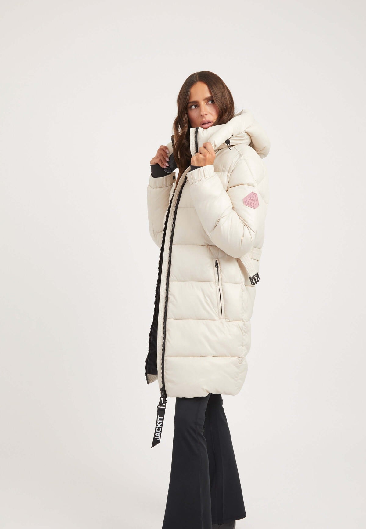Model wearing the EZ Belted Coat Stone, a womens belted puffer coat, featuring a tapered design and grown-on hood.
