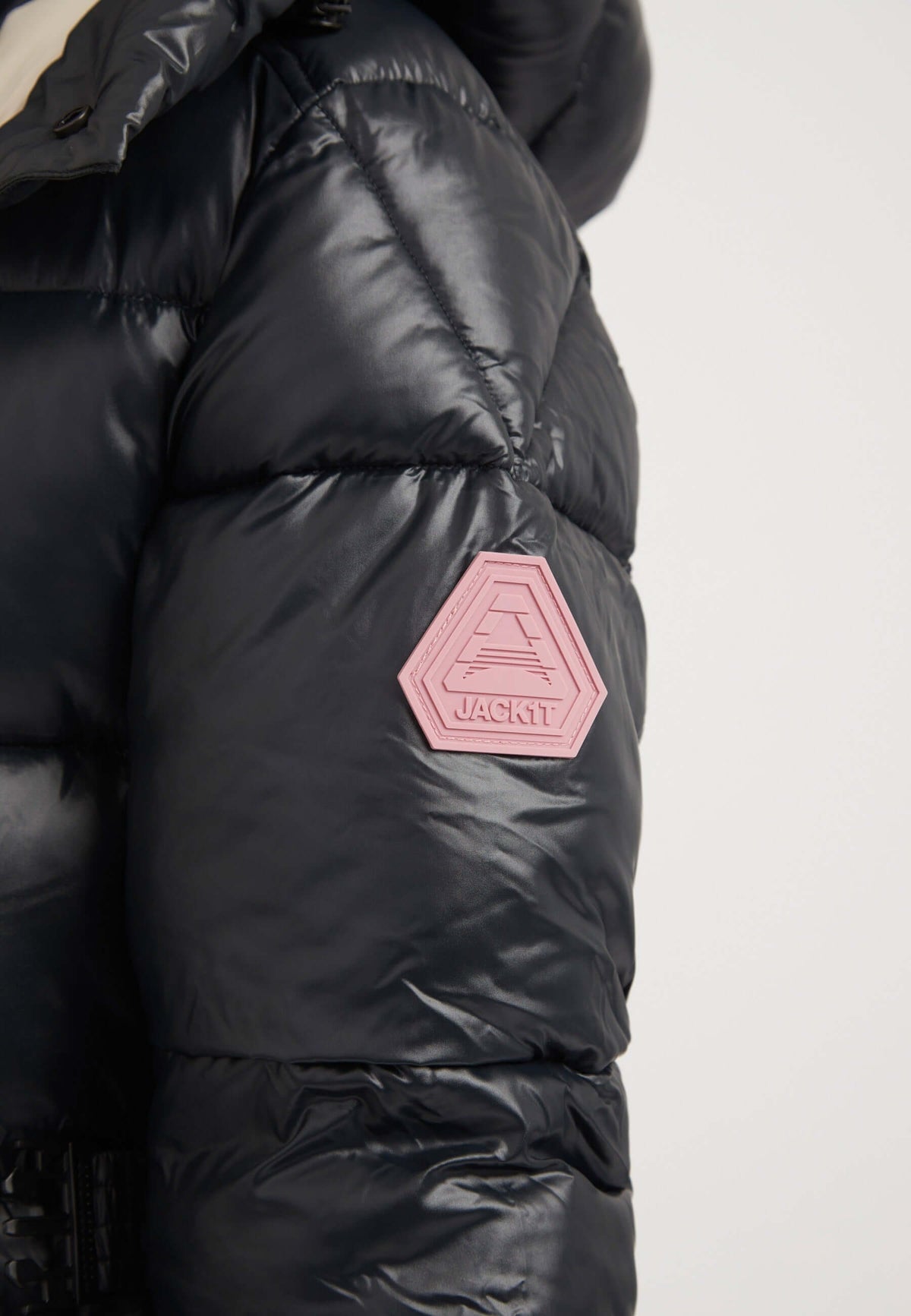 Close-up of the sleeve of a womens belted coat black with pink logo detail on a puffer jacket.
