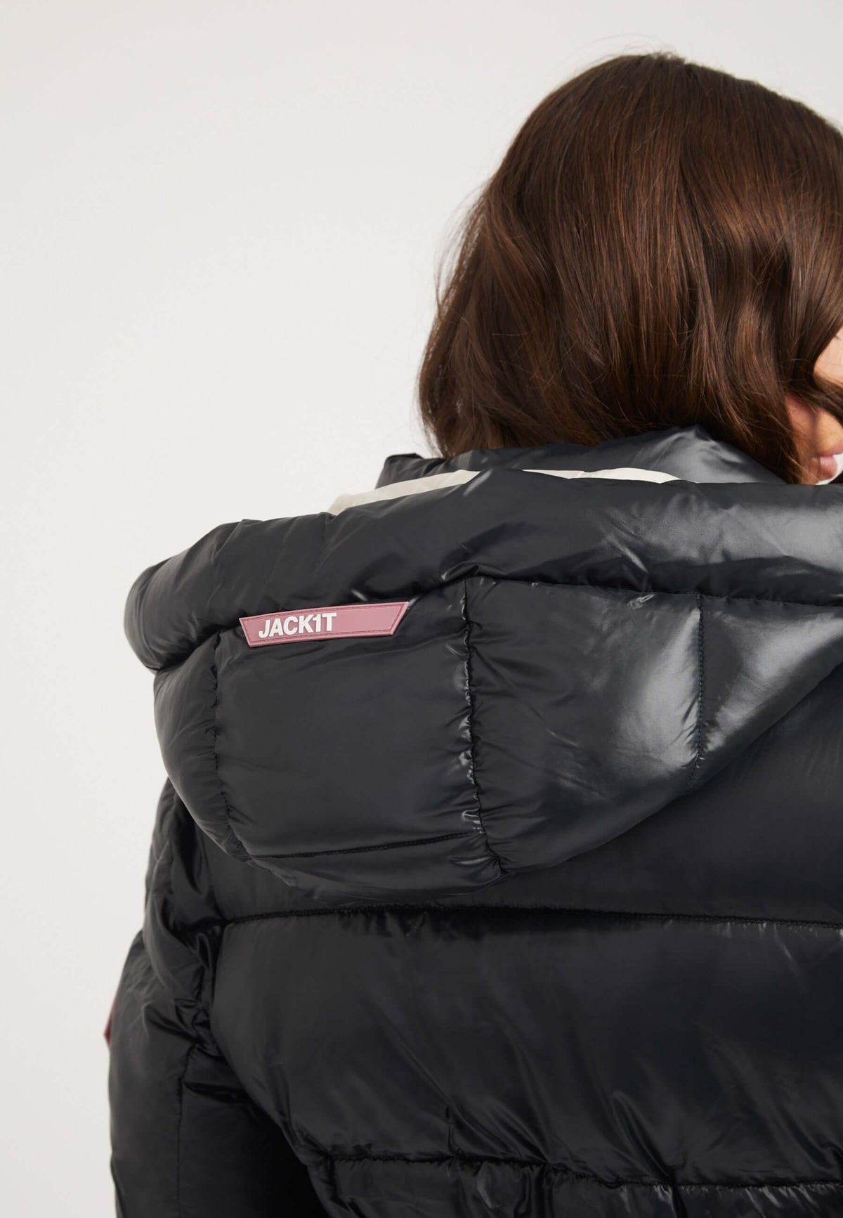Close-up of the back of a womens belted coat black featuring a hood and JACKIT brand label.