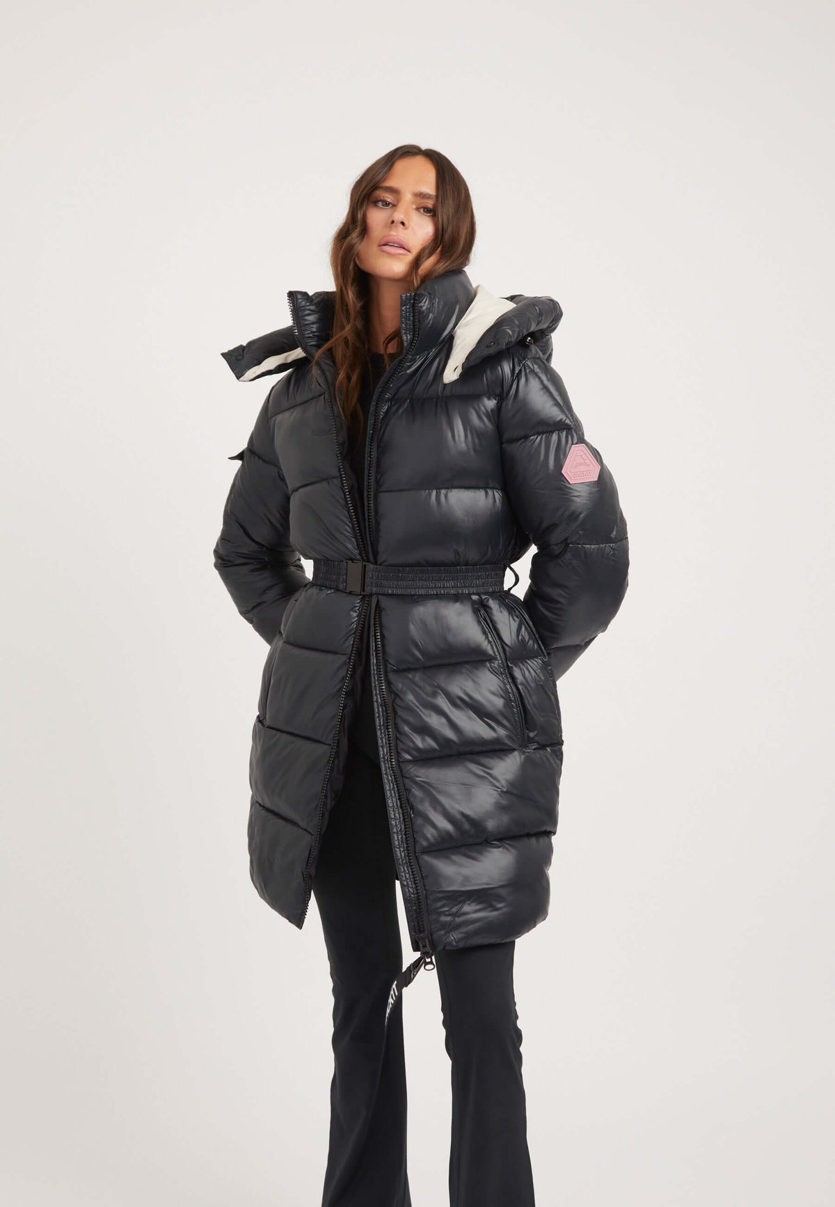 Model wearing womens belted coat black with tapered design and polished metal buckle.