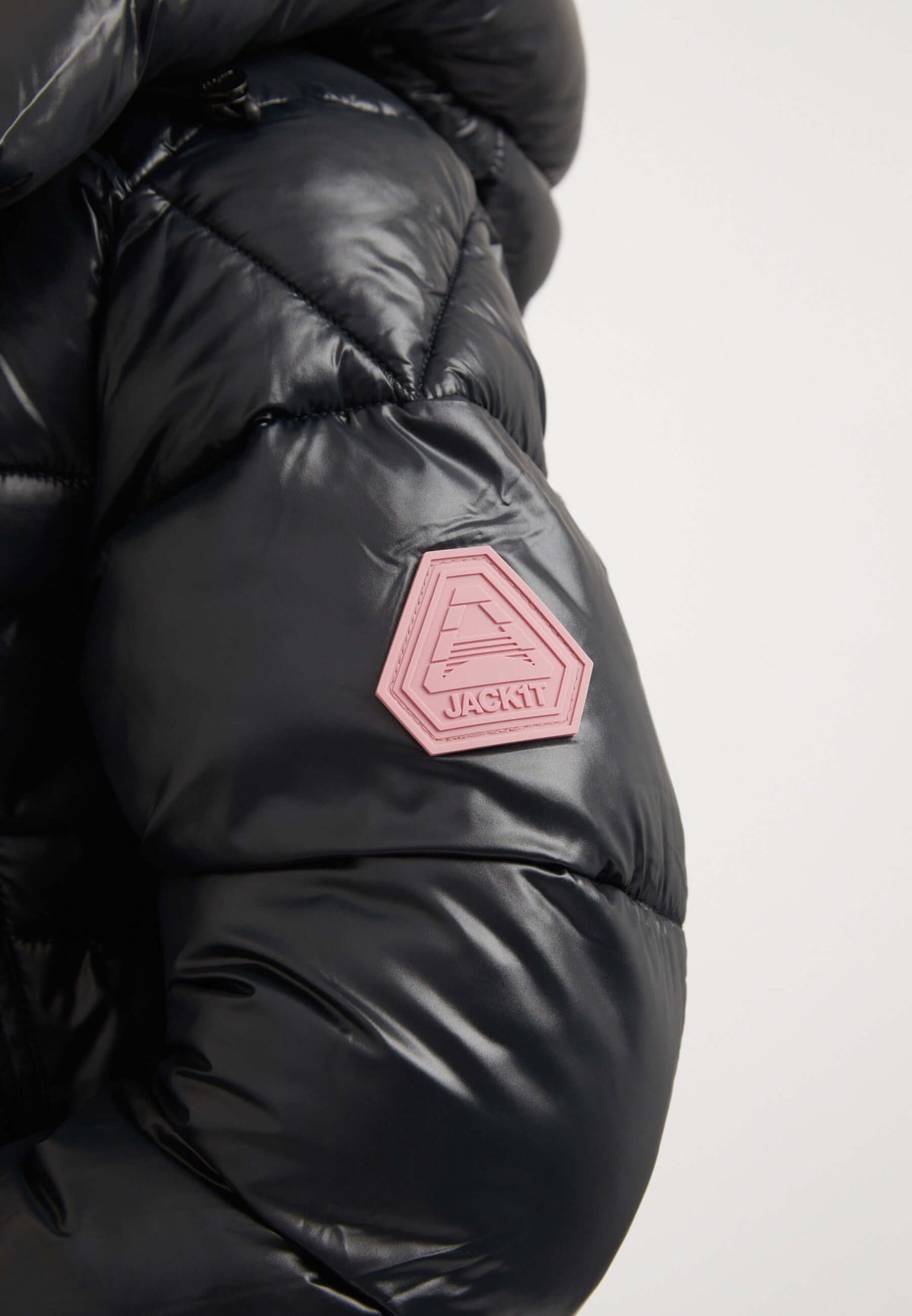 Close-up of EZ Box Crop Jacket Black featuring logo patch on sleeve, showcasing stylish design of a short puffer jacket women.