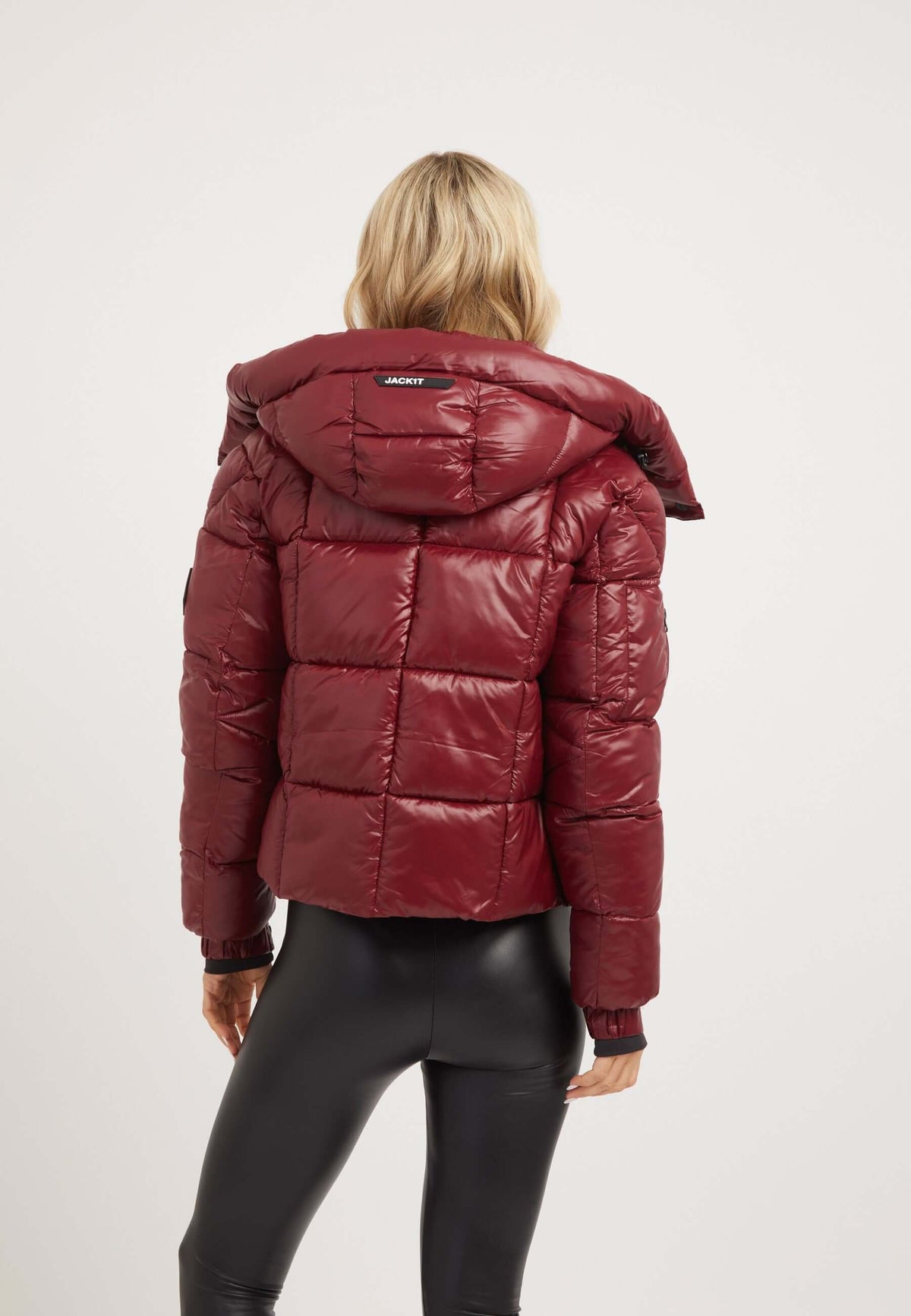 Back view of a woman wearing a dark cranberry cropped puffer jacket, showcasing 'short puffer jacket women' style.